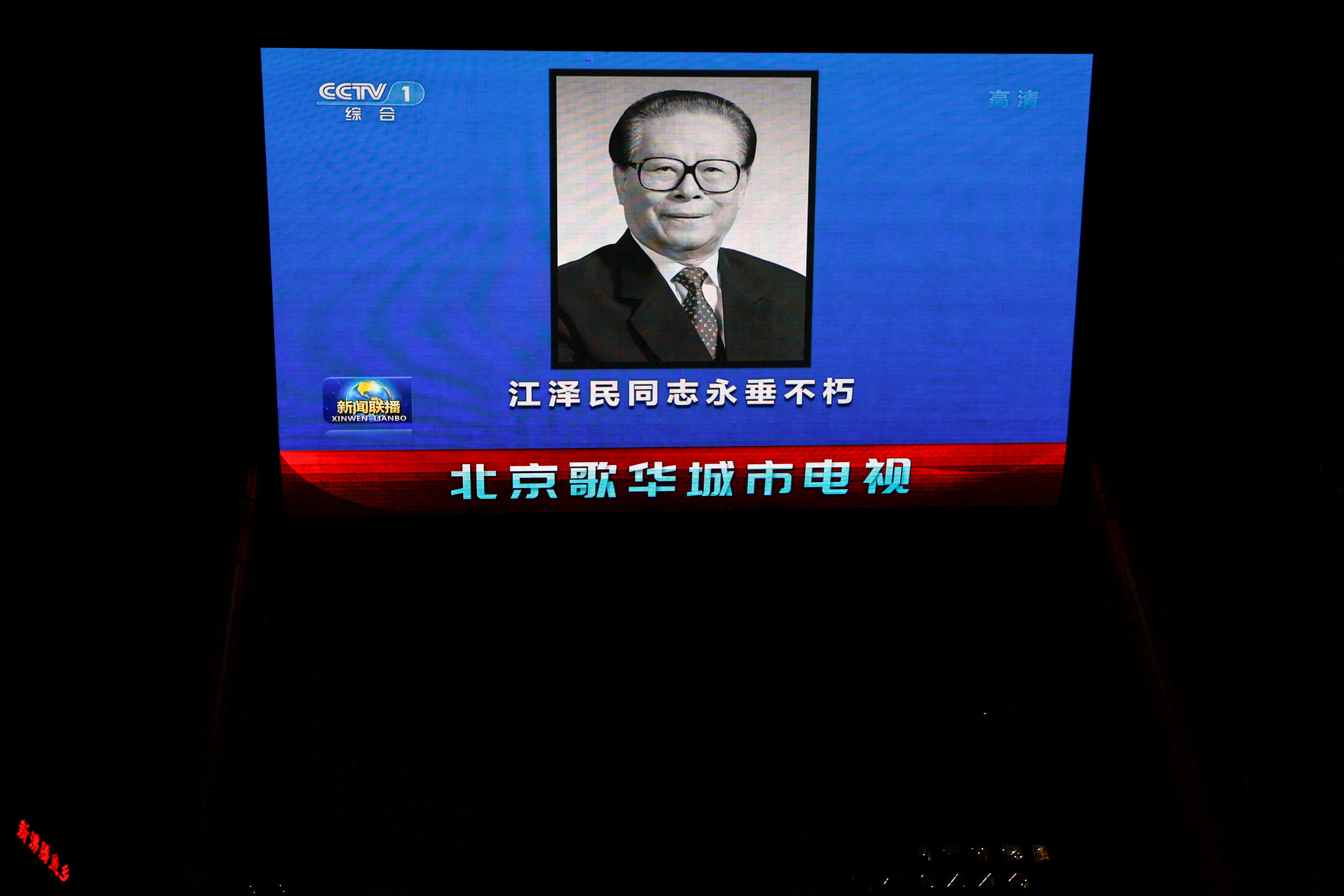 A screen broadcasts news footage of former Chinese President Jiang Zemin following his death, in Beijing