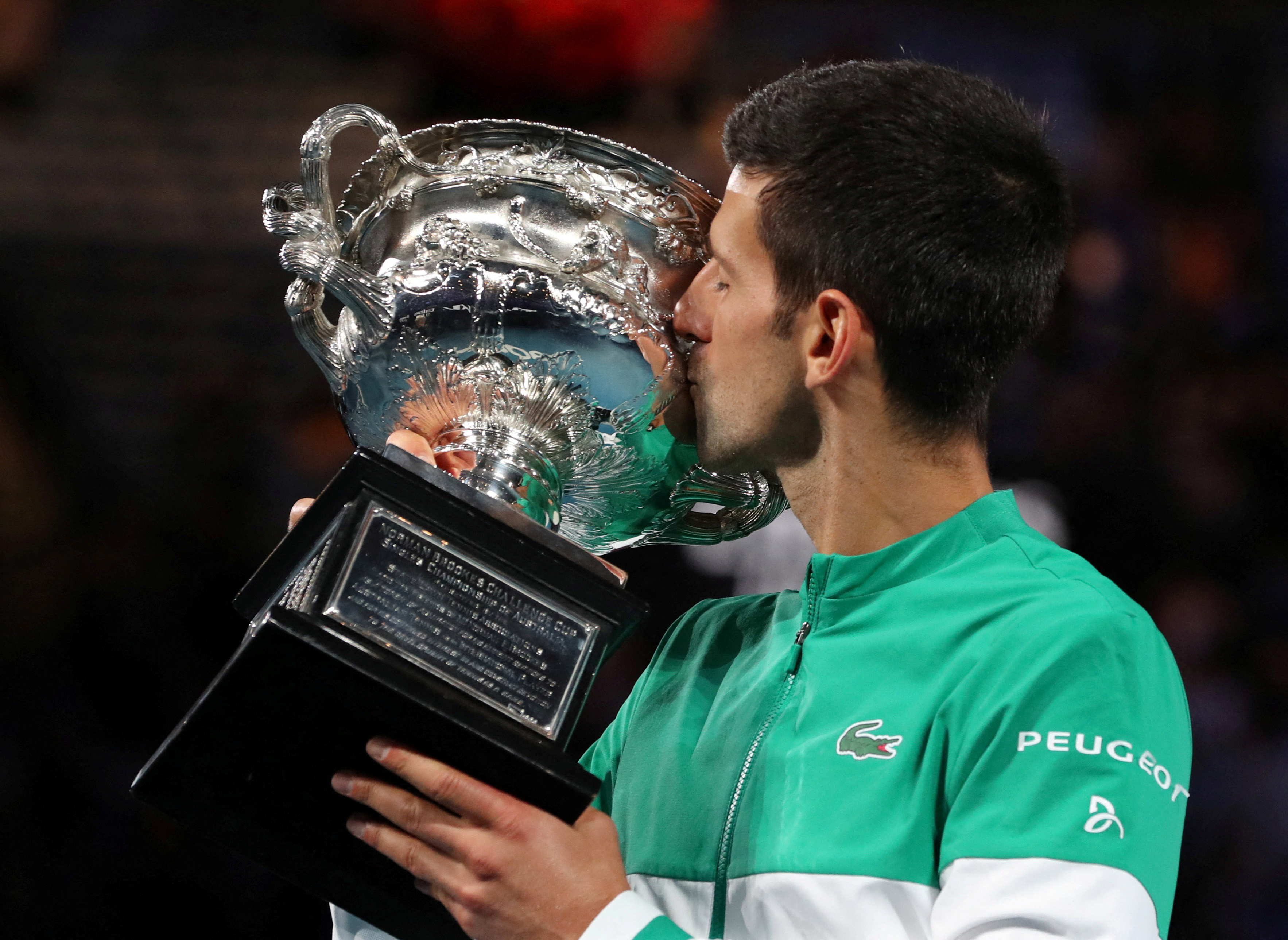 Serbia's Novak Djokovic celebrates with the trophy after winning his ninth Australian Open title