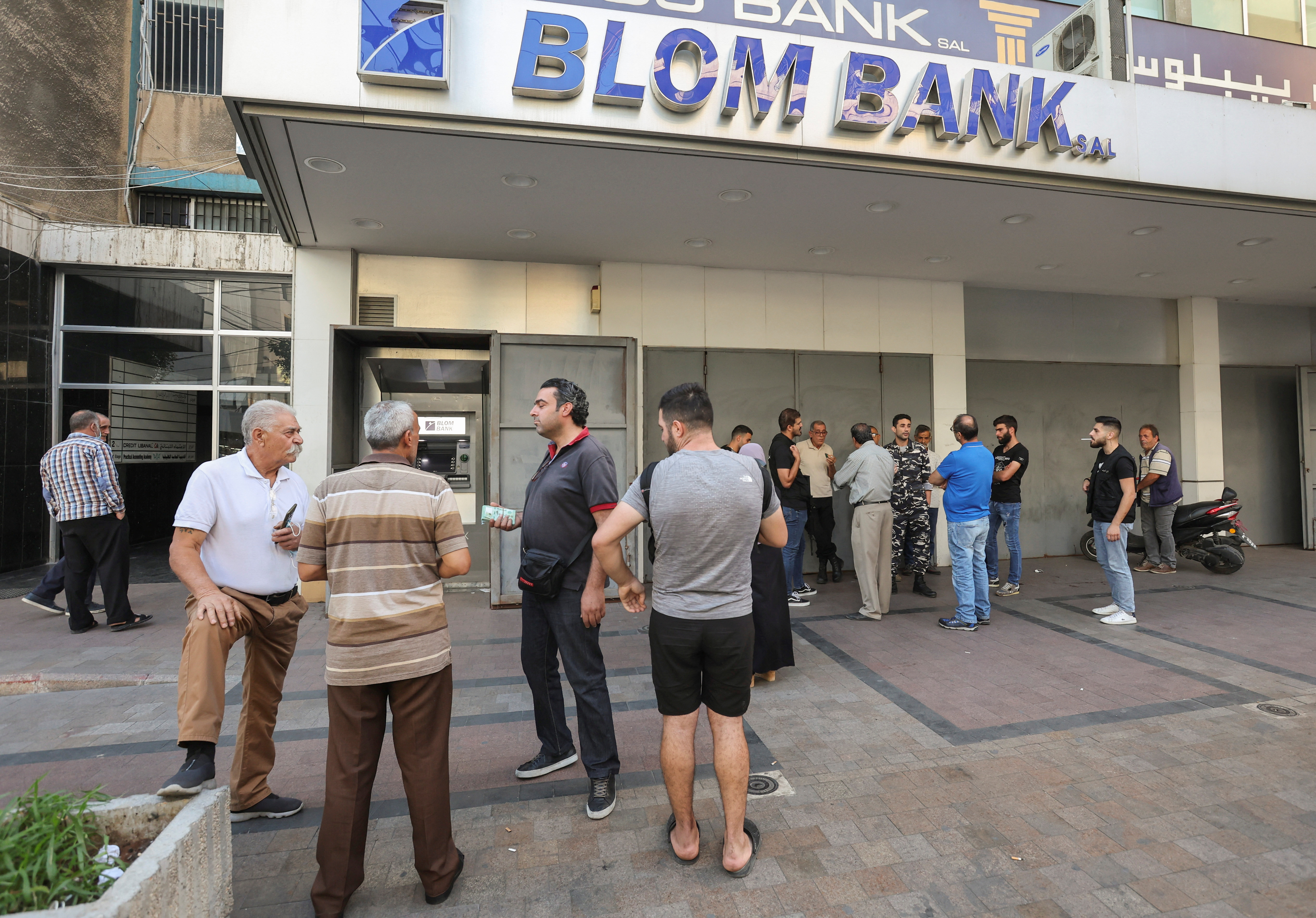 People wait outside a Blom Bank branch in Sidon