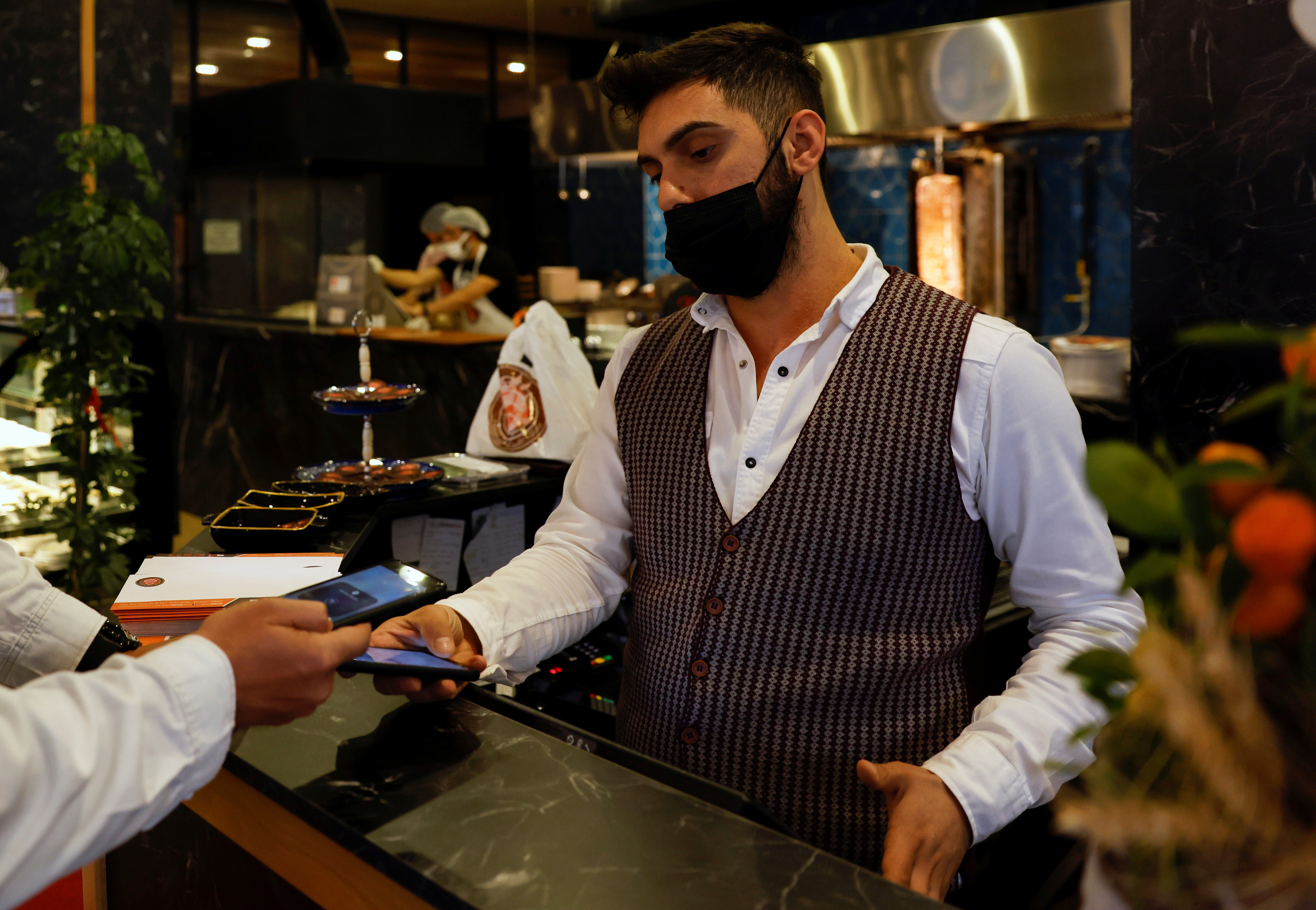 glA cashier recieves a payment via a cryptocurrency app at a kebab restaurant that accepts Bitcoin and Dexchain in Istanbul