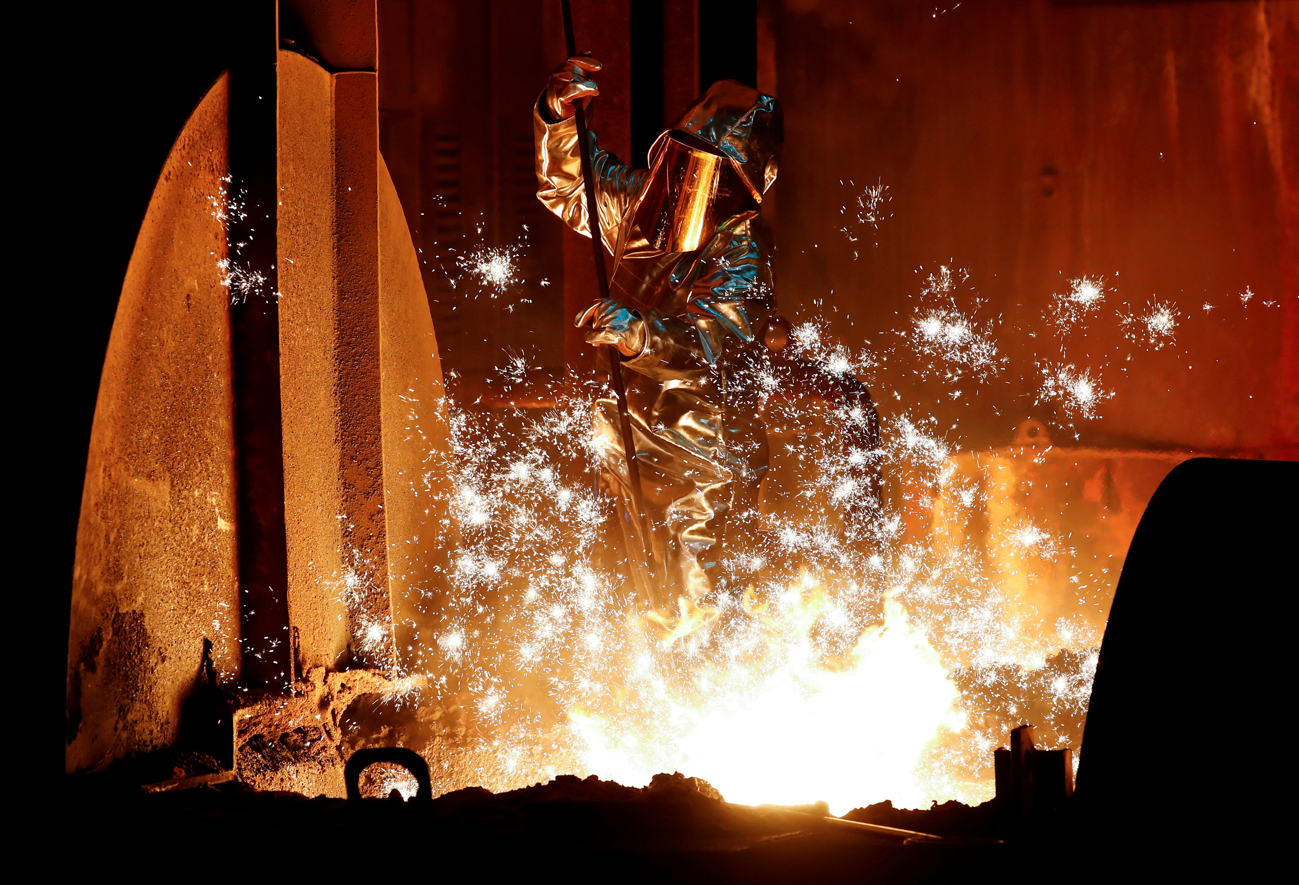 A steel worker of Germany's industrial conglomerate ThyssenKrupp AG takes a sample of raw iron from a blast furnace at Europe's largest steel factory in Duisburg