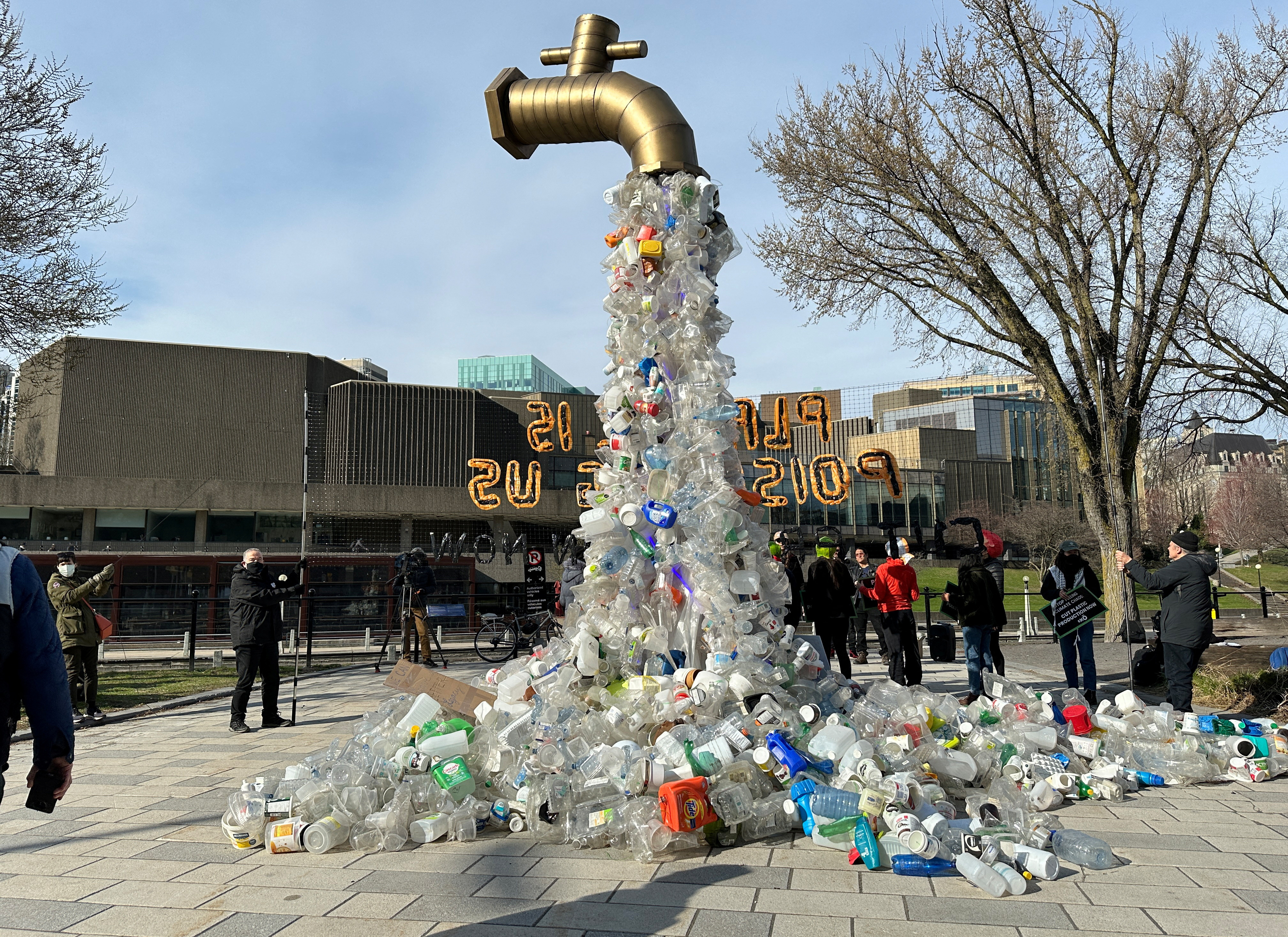 Prop depicting a water tap with plastic bottle pollution is displayed by activists in Ottawa
