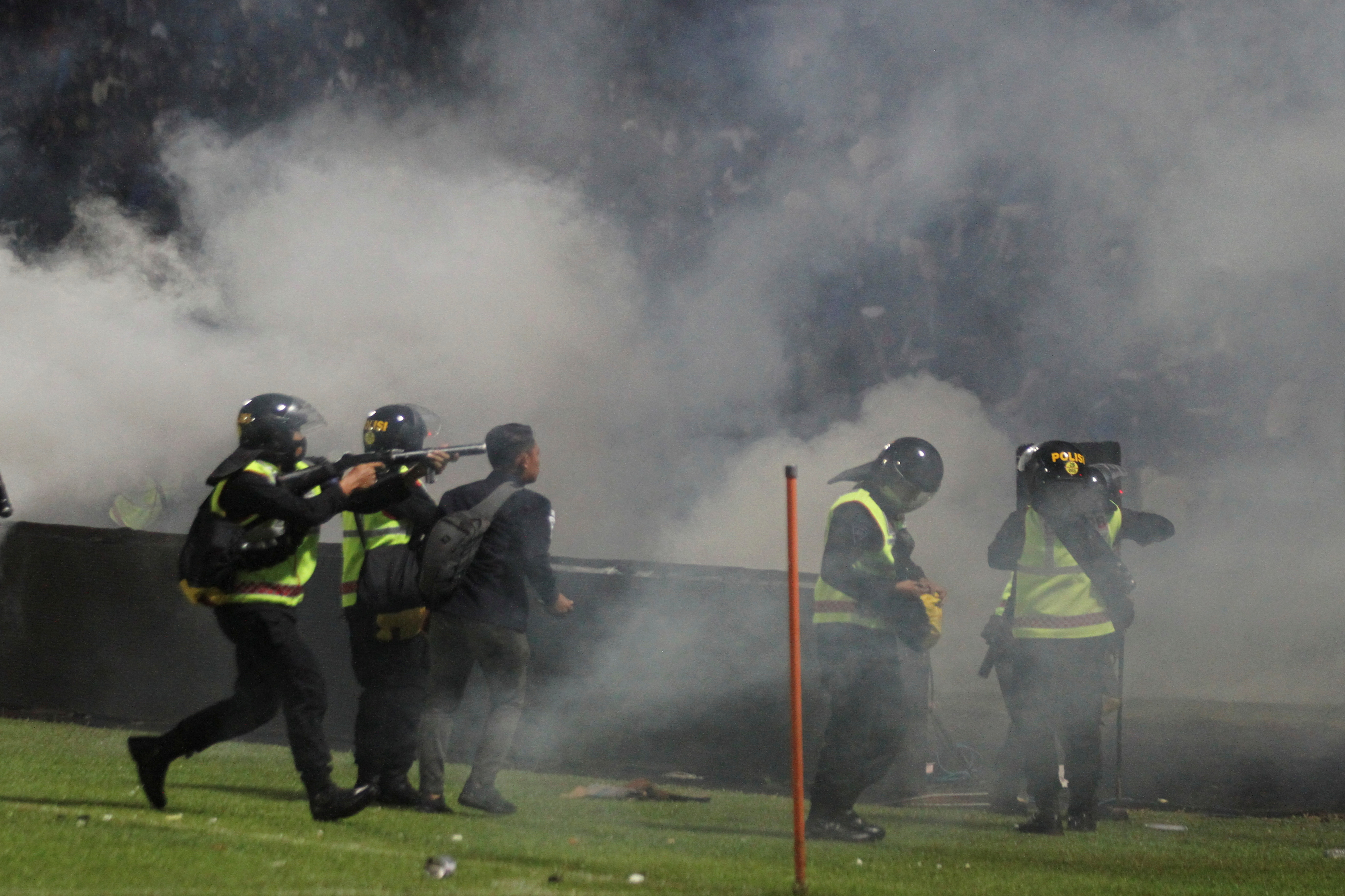 A riot police officer fires tear gas after the football match between Arema vs Persebaya at Kanjuruhan Stadium in Malang
