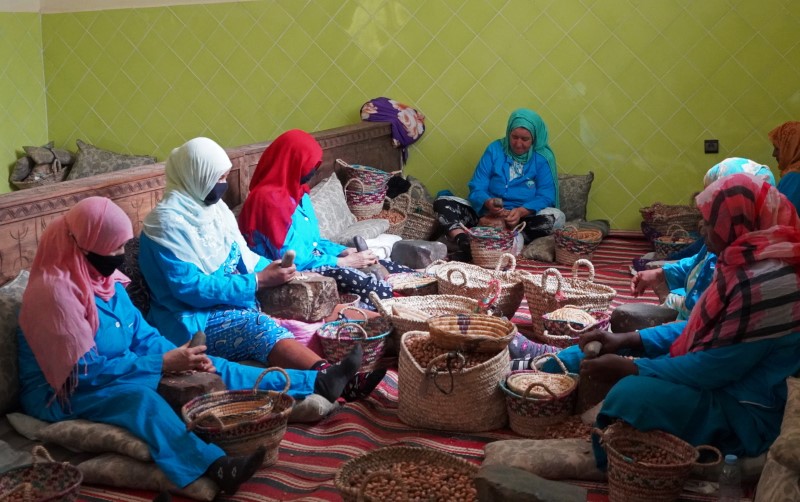 Amazigh women sit together as they crush argan nuts to extract the kernels in Tiout, near Taroudant
