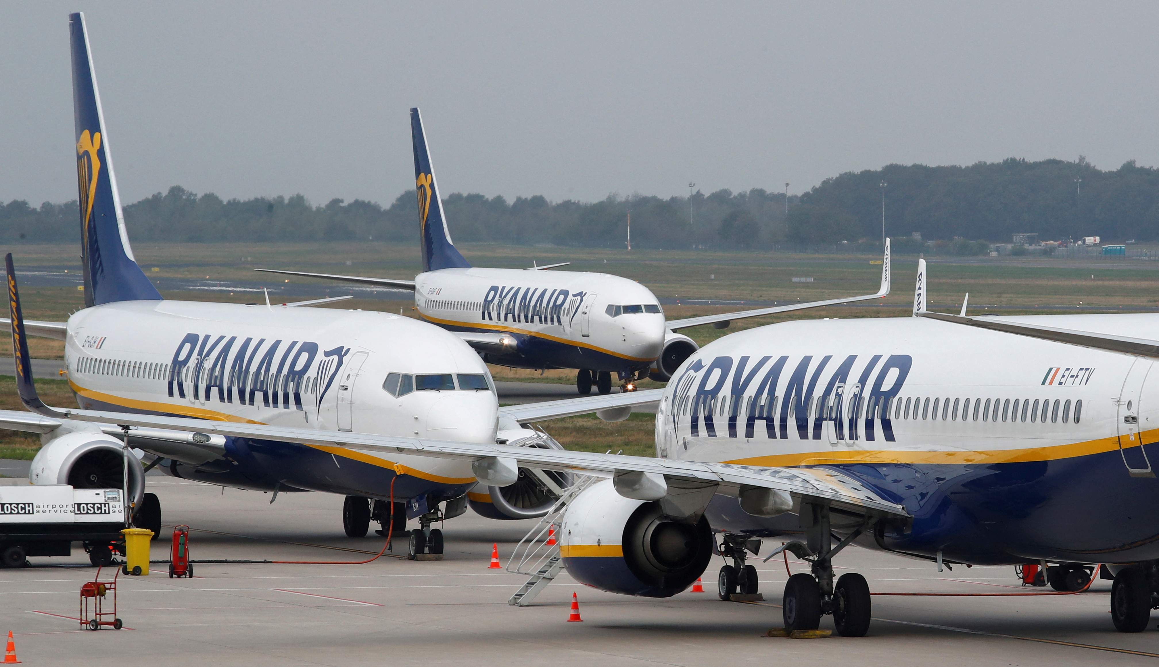 Ryanair airplane taxis past two parked aircraft at Weeze Airport