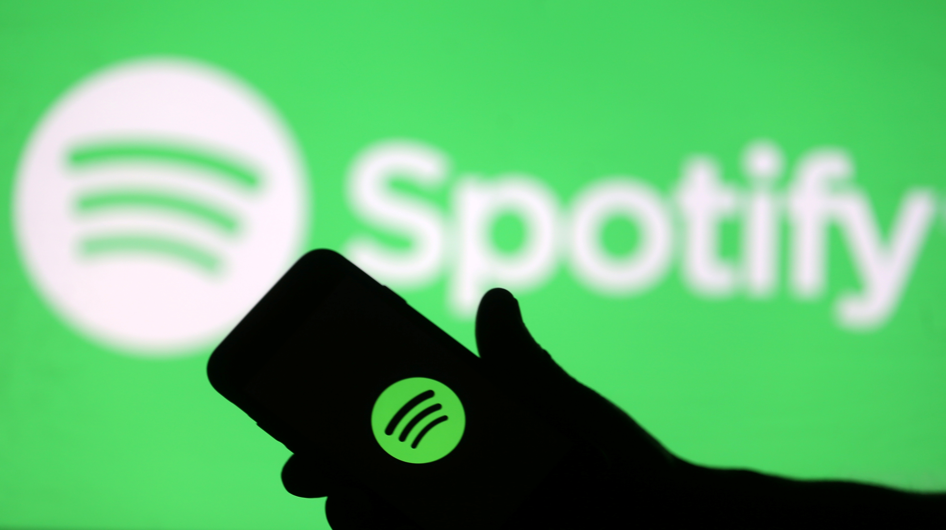 A smartphone is seen in front of a screen projection of Spotify logo, in this picture illustration taken April 1, 2018. REUTERS/Dado Ruvic/Illustration
