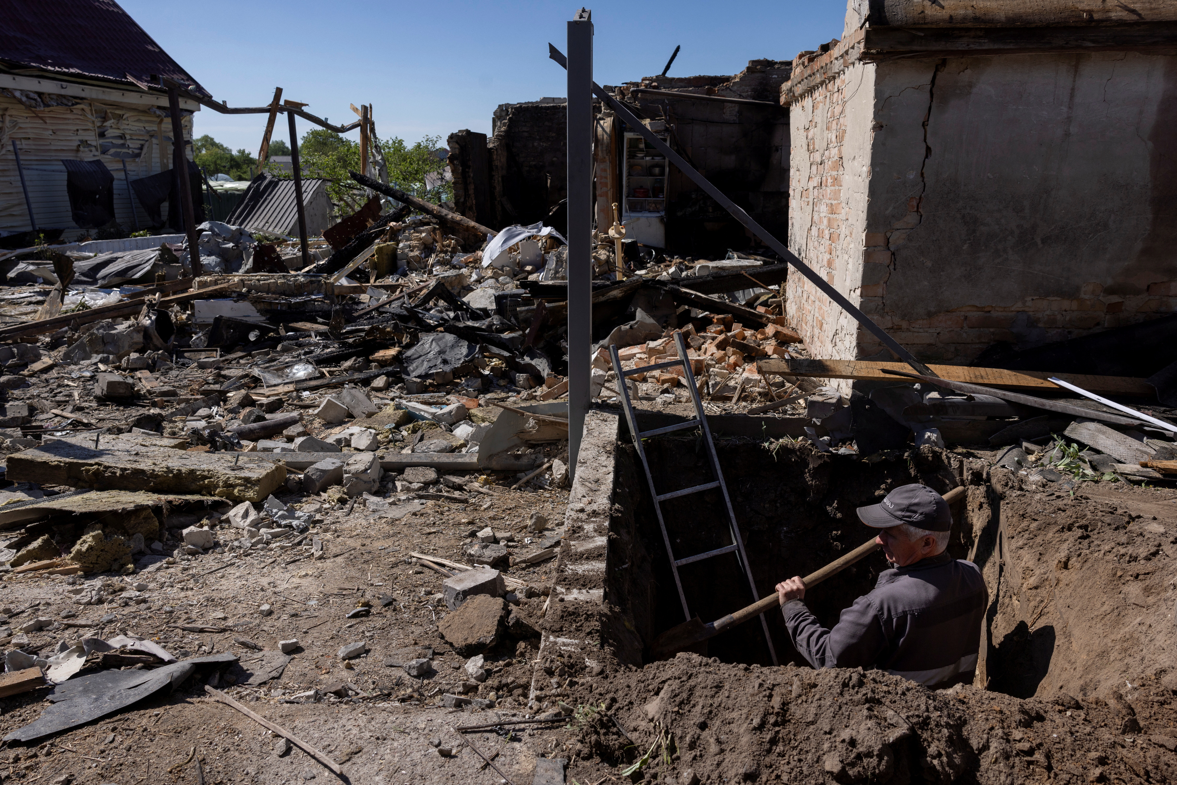A worker digs to uncover a gas pipe leading to a house that was destroyed during a Russian missile strike in Krasylivka