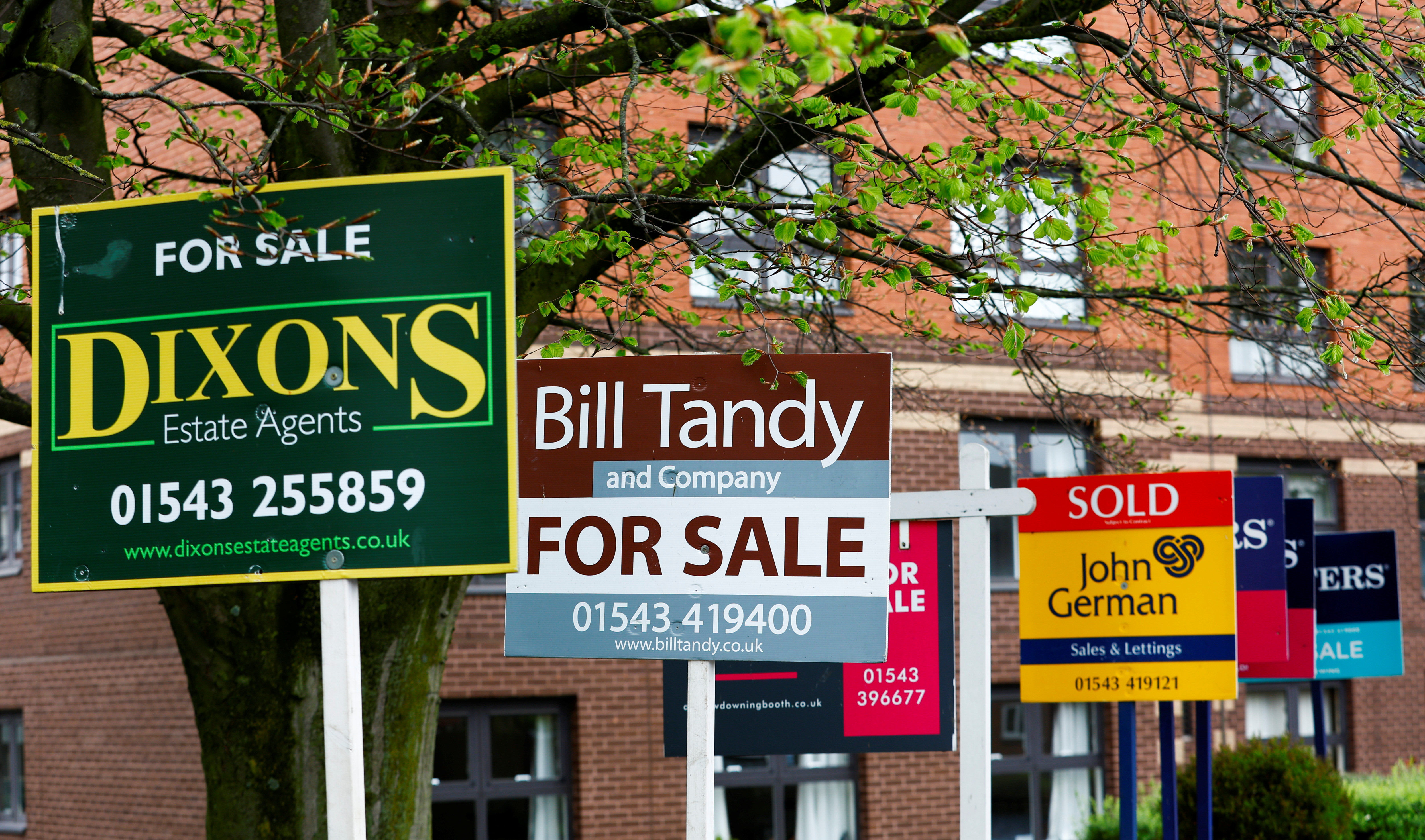 Property estate agent sales and letting signs are seen outside an apartment building