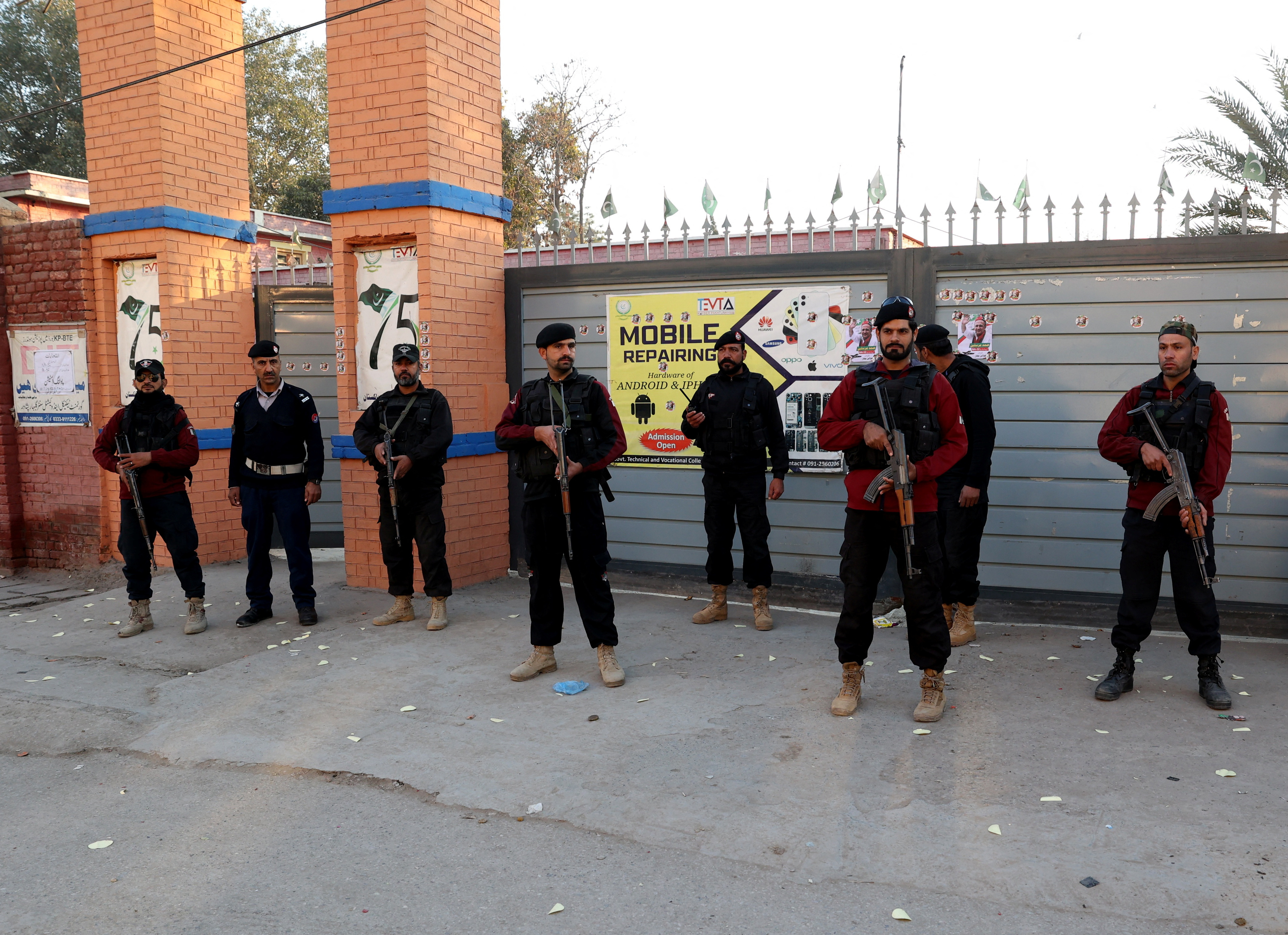 Police officers stand guard outside a polling station in Gulbahar area in Peshawar