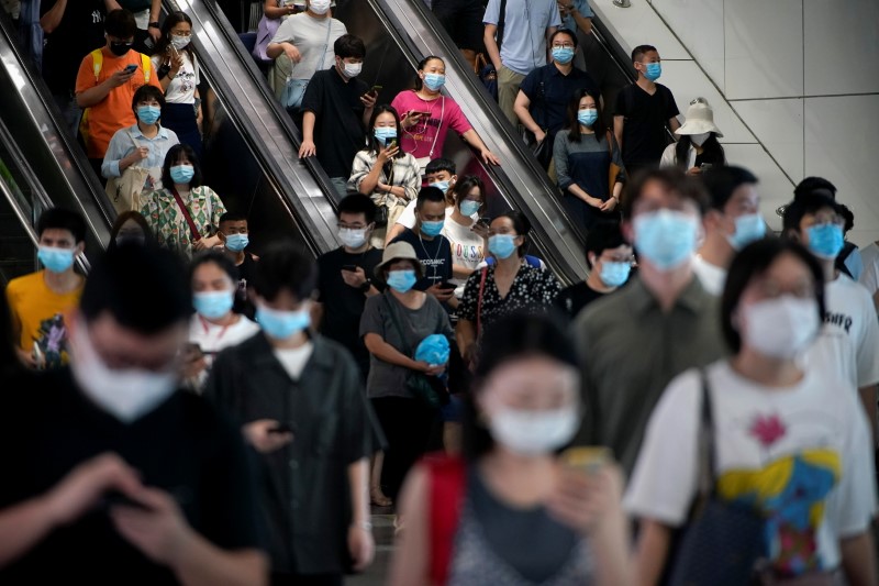 People wearing protective masks ride escalators inside a subway station, following new cases of the coronavirus disease (COVID-19), in Shanghai