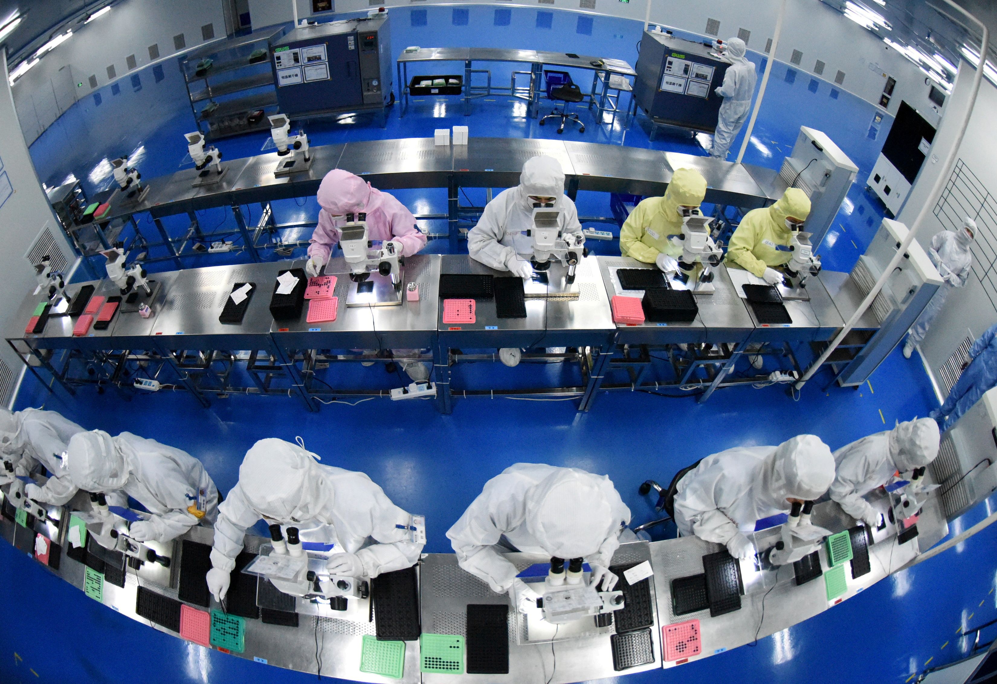 Employees work on a production line manufacturing camera lenses for cellphones at a factory in Lianyungang, Jiangsu province, China April 30, 2019. Picture taken with a fisheye lens. China Daily via REUTERS