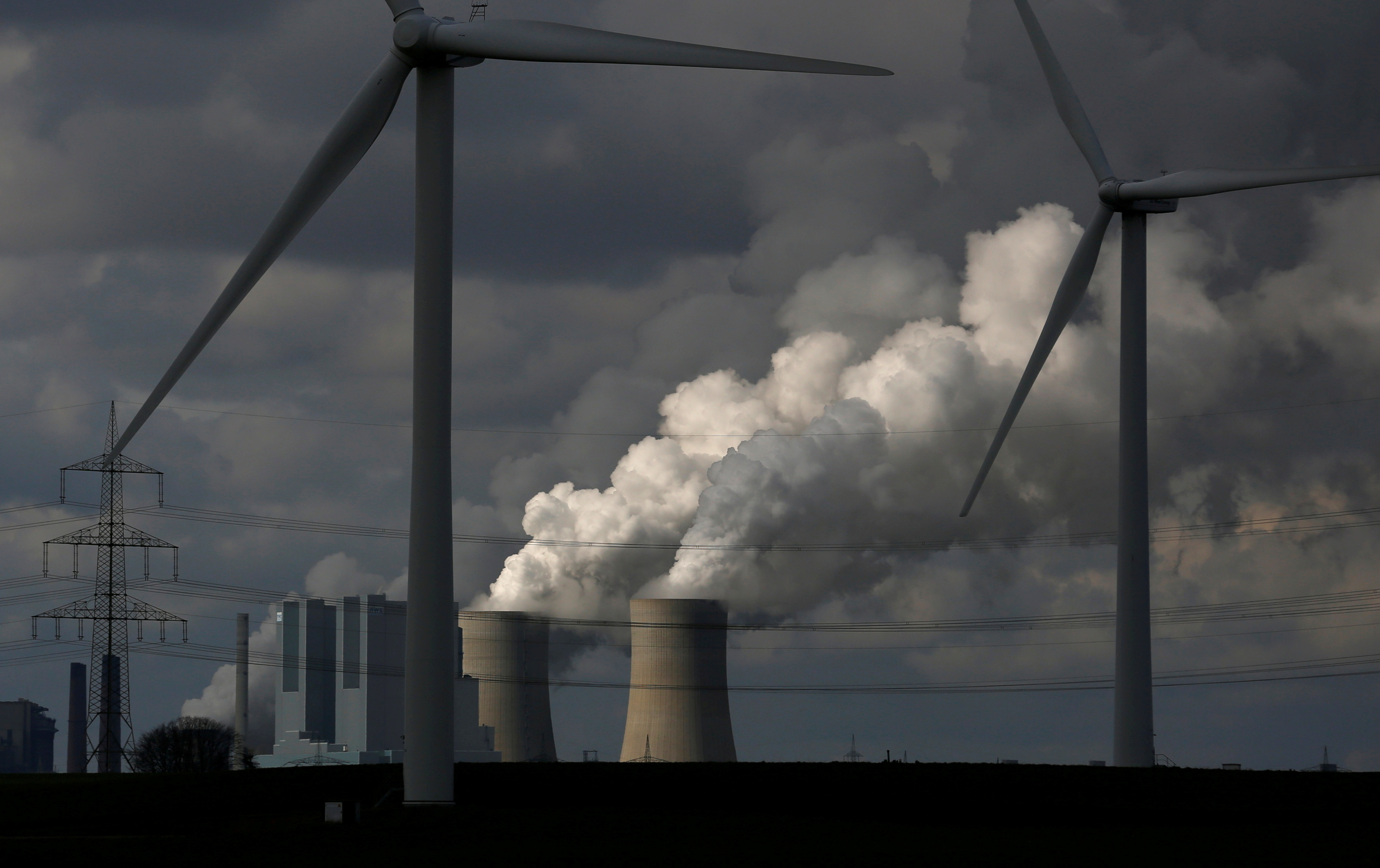 Wind turbines are seen in front of a coal power plant of German utility RWE Power near Neurath