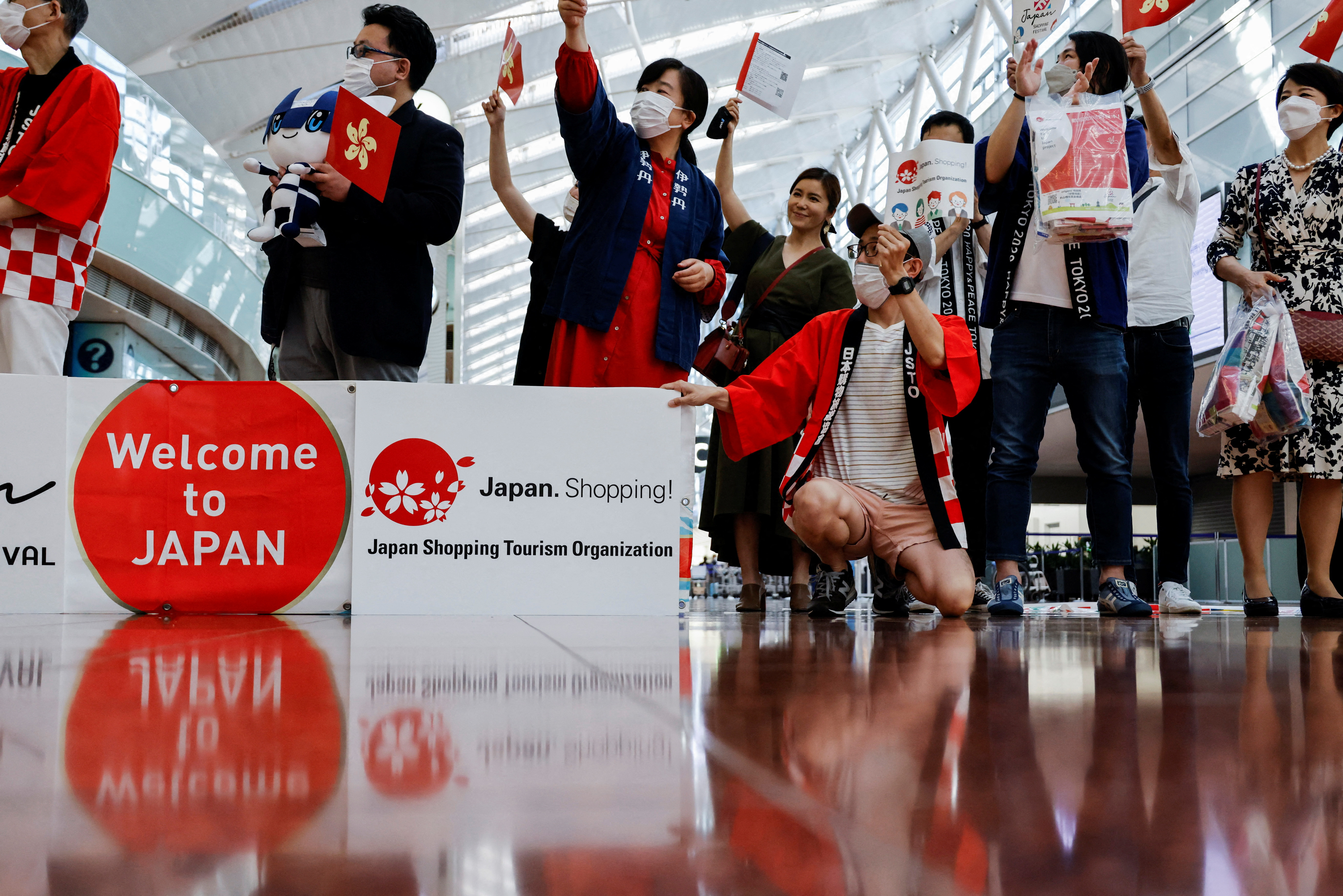 Members from Japan's shopping and tourism companies greet a group of tourists from Hong Kong during an welcome event at Haneda airport in Tokyo