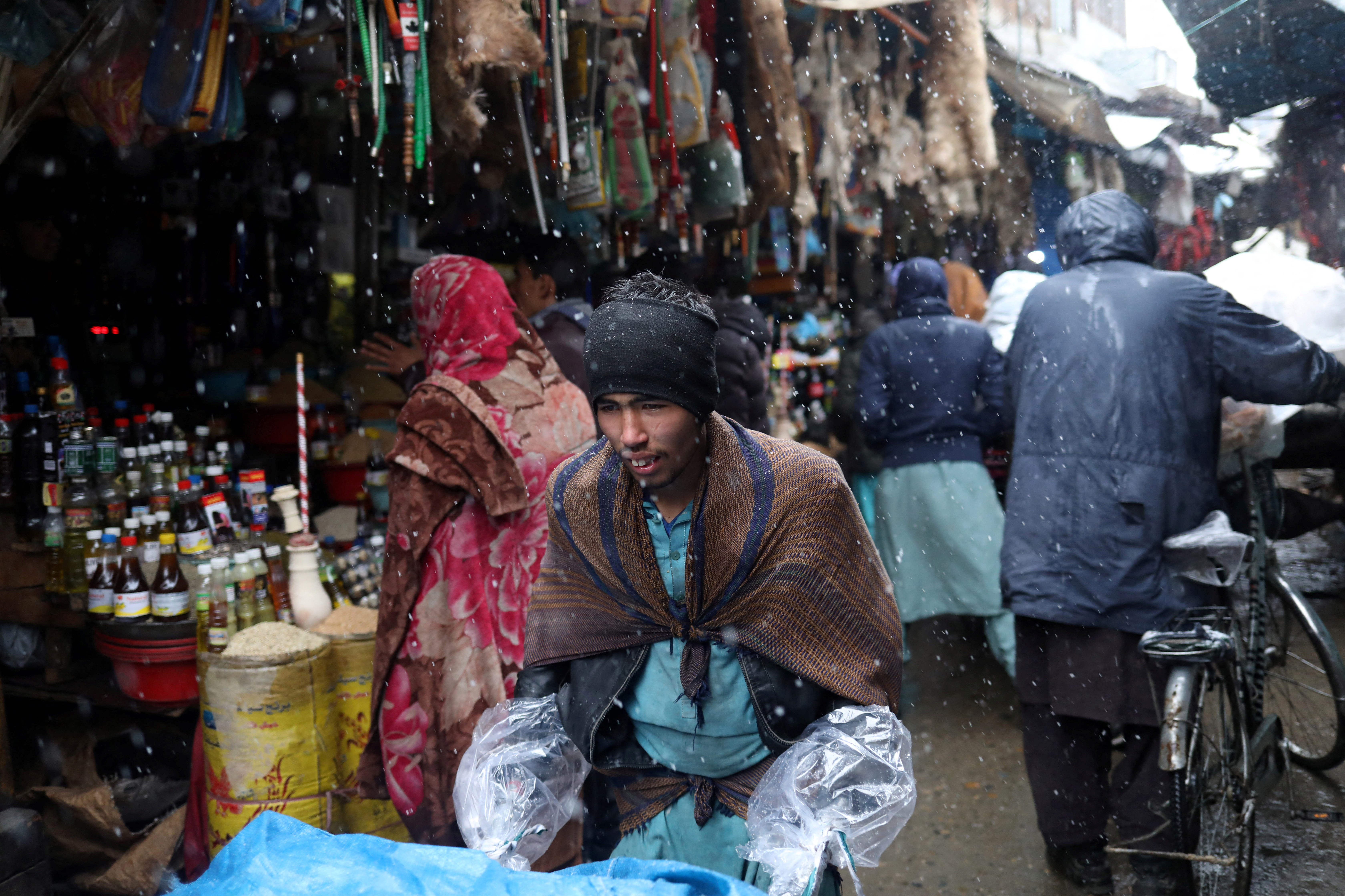Afghan men walk in a market area during a snowfall in Kabul, Afghanistan, January 3, 2022. REUTERS/Ali Khara
