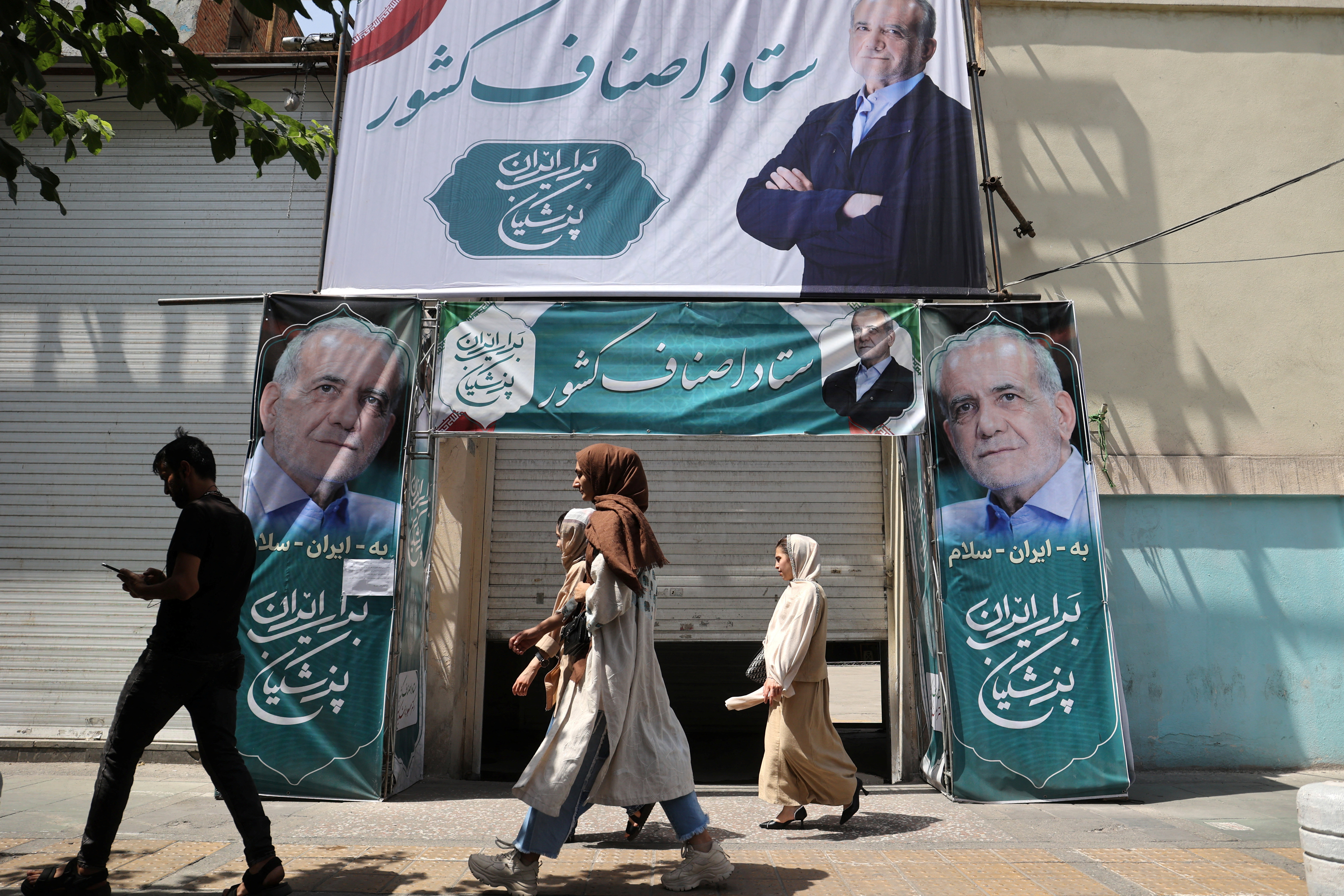 A banner featuring presidential candidate Masoud Pezeshkian is displayed on a street in Tehran