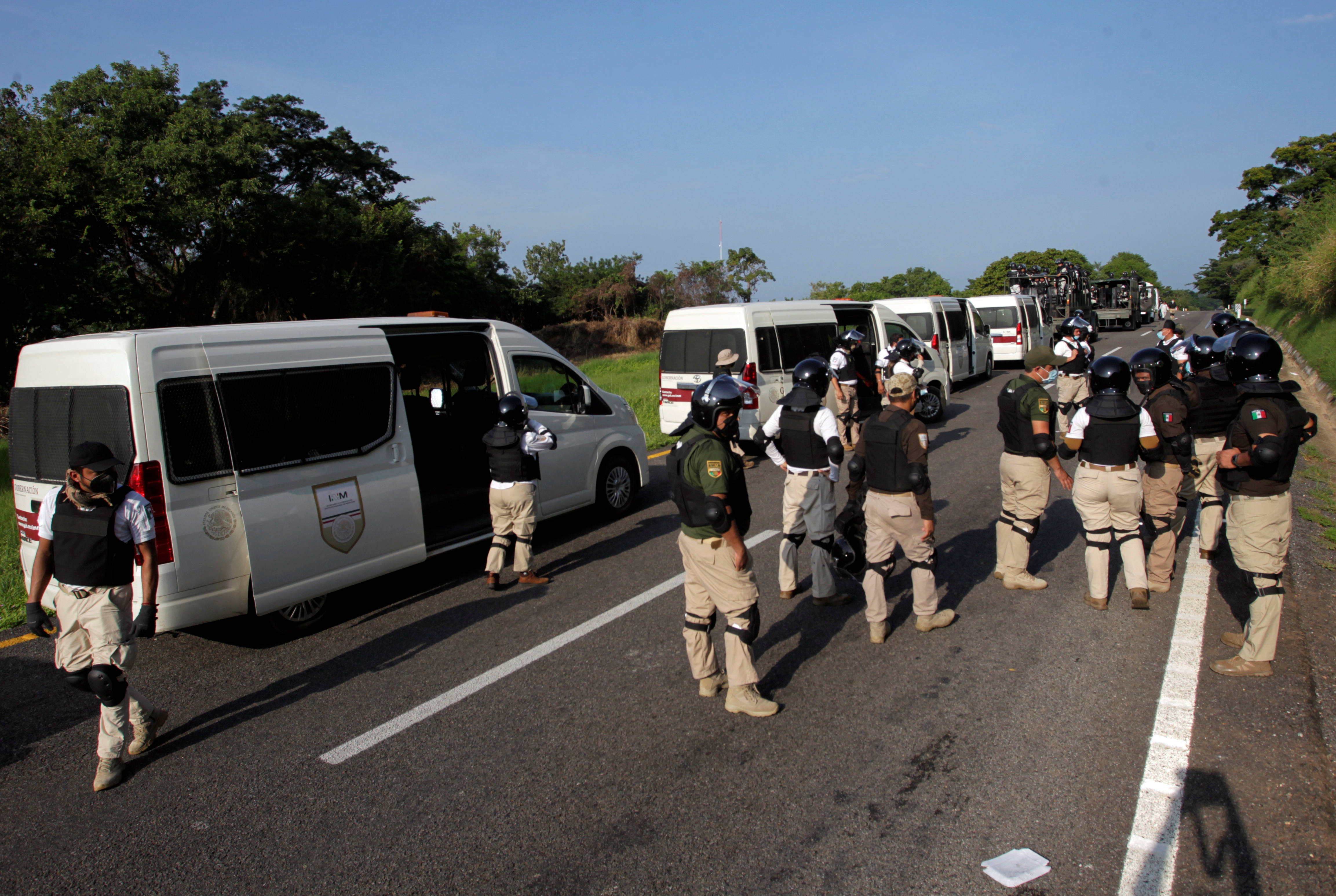 Agents of the National Institute of Migration (INM) and members of the National Guard follow a migrant caravan, in Pijijiapan