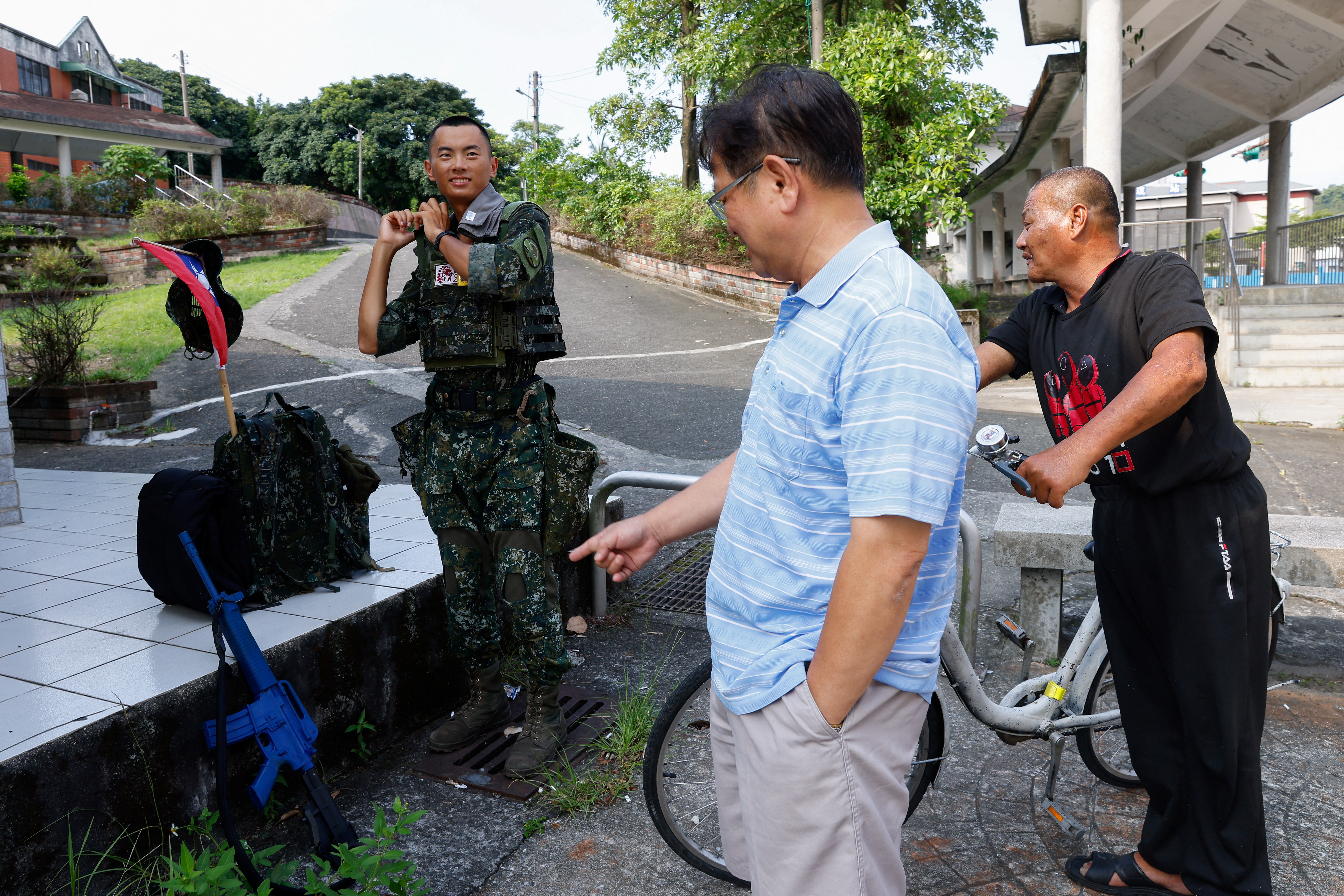 People chat and point at Tsai Tsung-lin's plastic rifle, as he gets ready to continue the walk to Taipei from Keelung