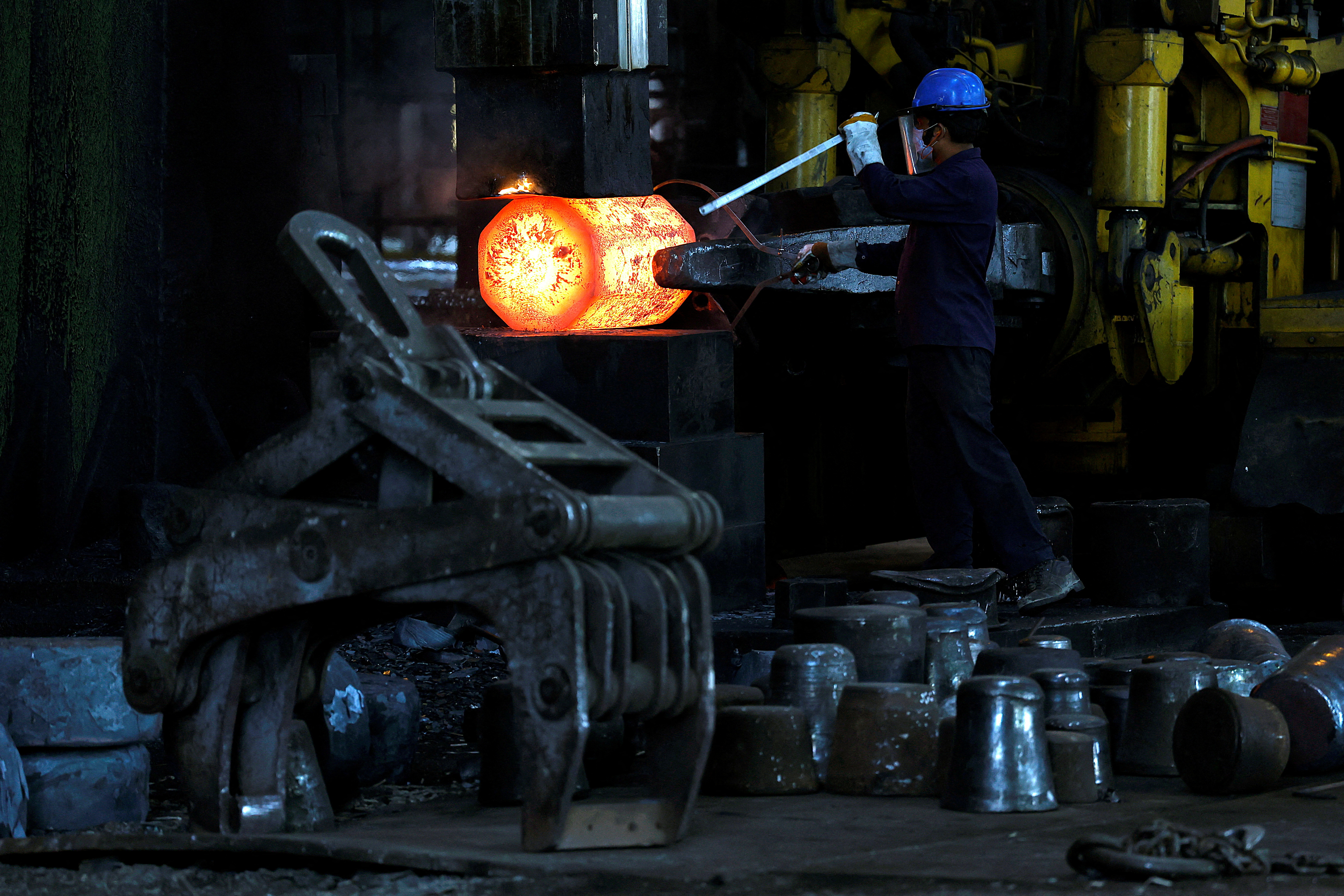 An employee moves forging red hot steel inside a factory in West Bengal