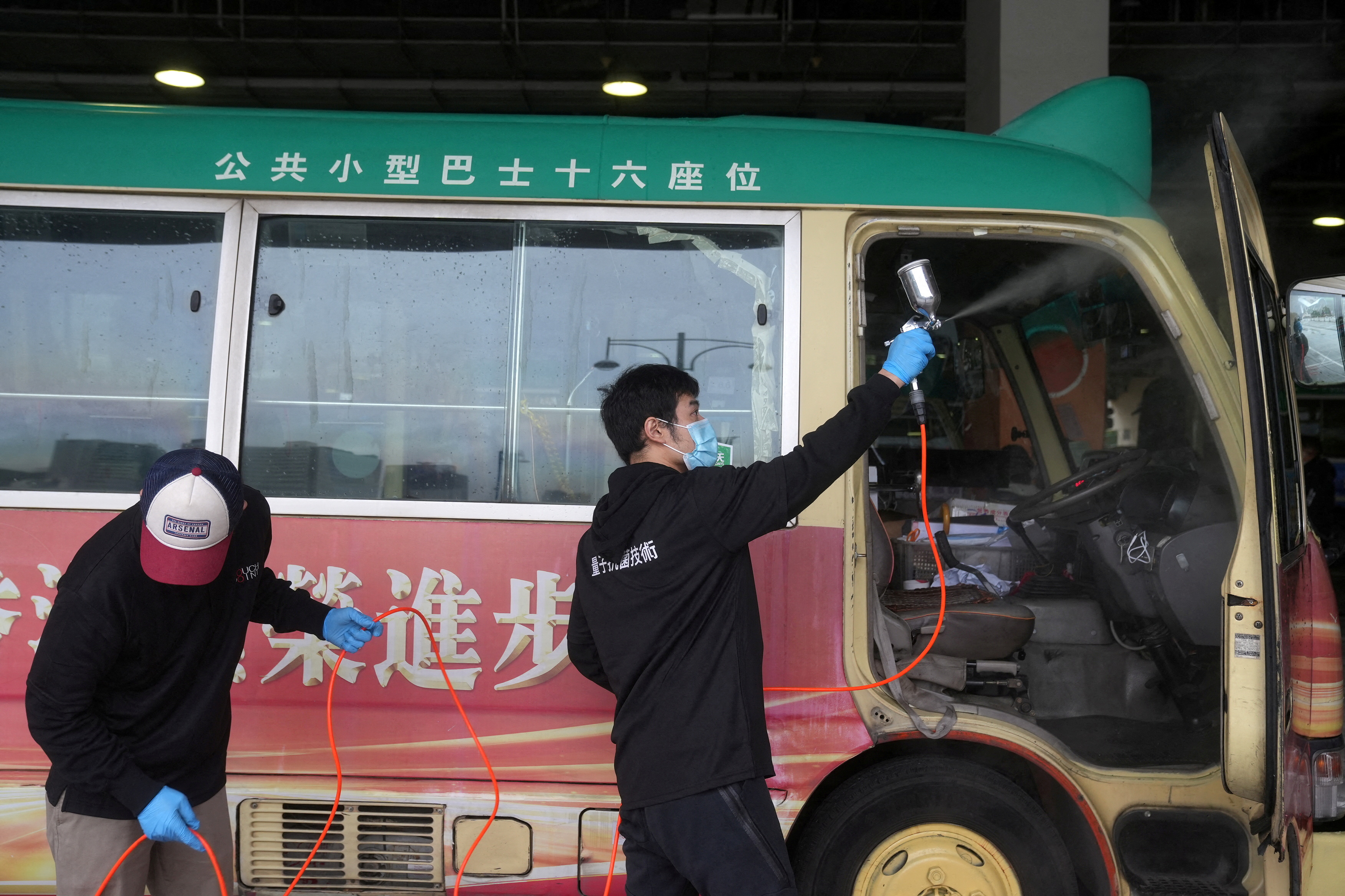 Cleaning staff spray disinfectant on a public minibus for driving coronavirus disease (COVID-19) patients, in Hong Kong, China