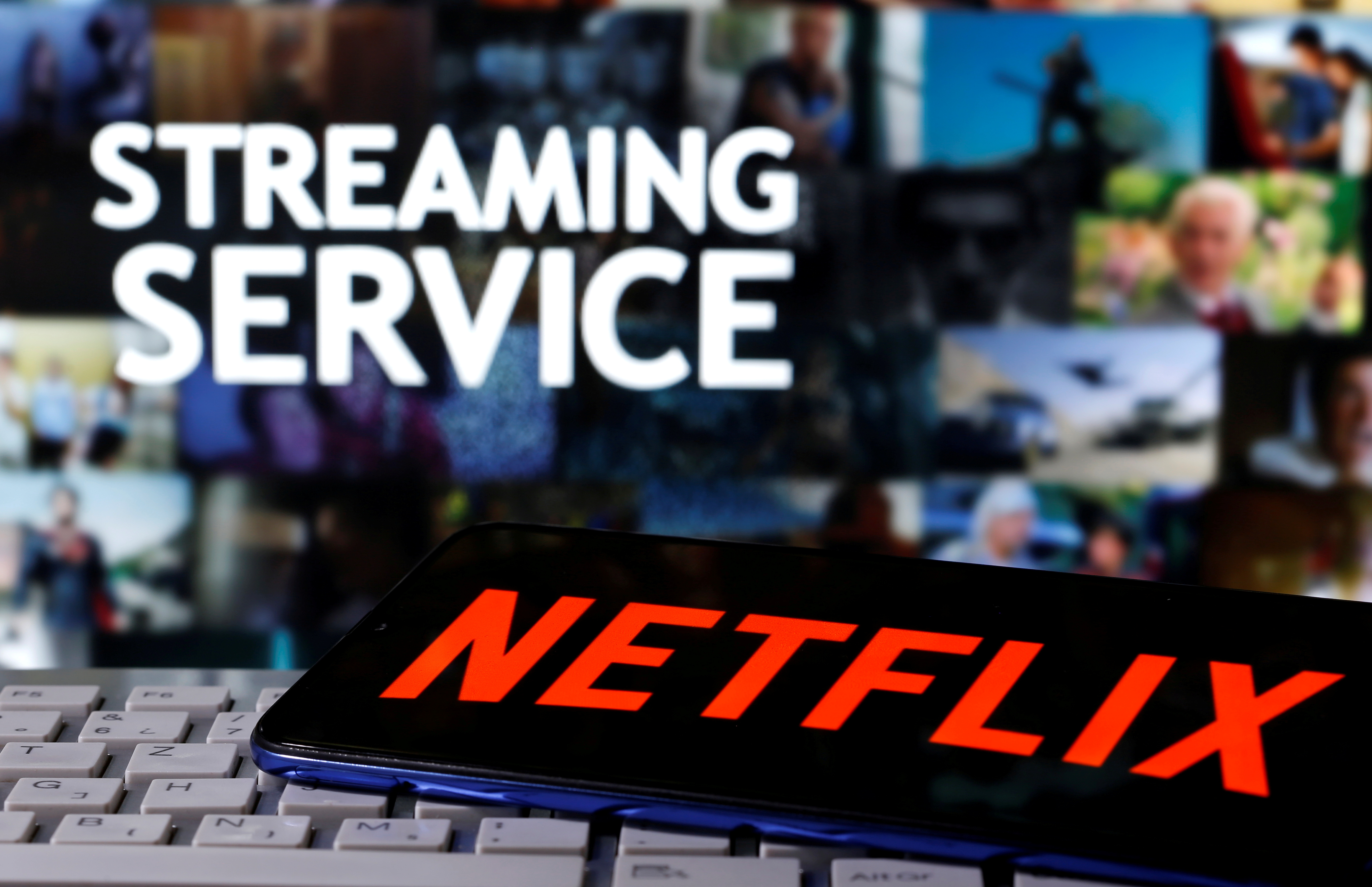 A smartphone with the Netflix logo is seen on a keyboard in front of displayed "Streaming service" words in this illustration