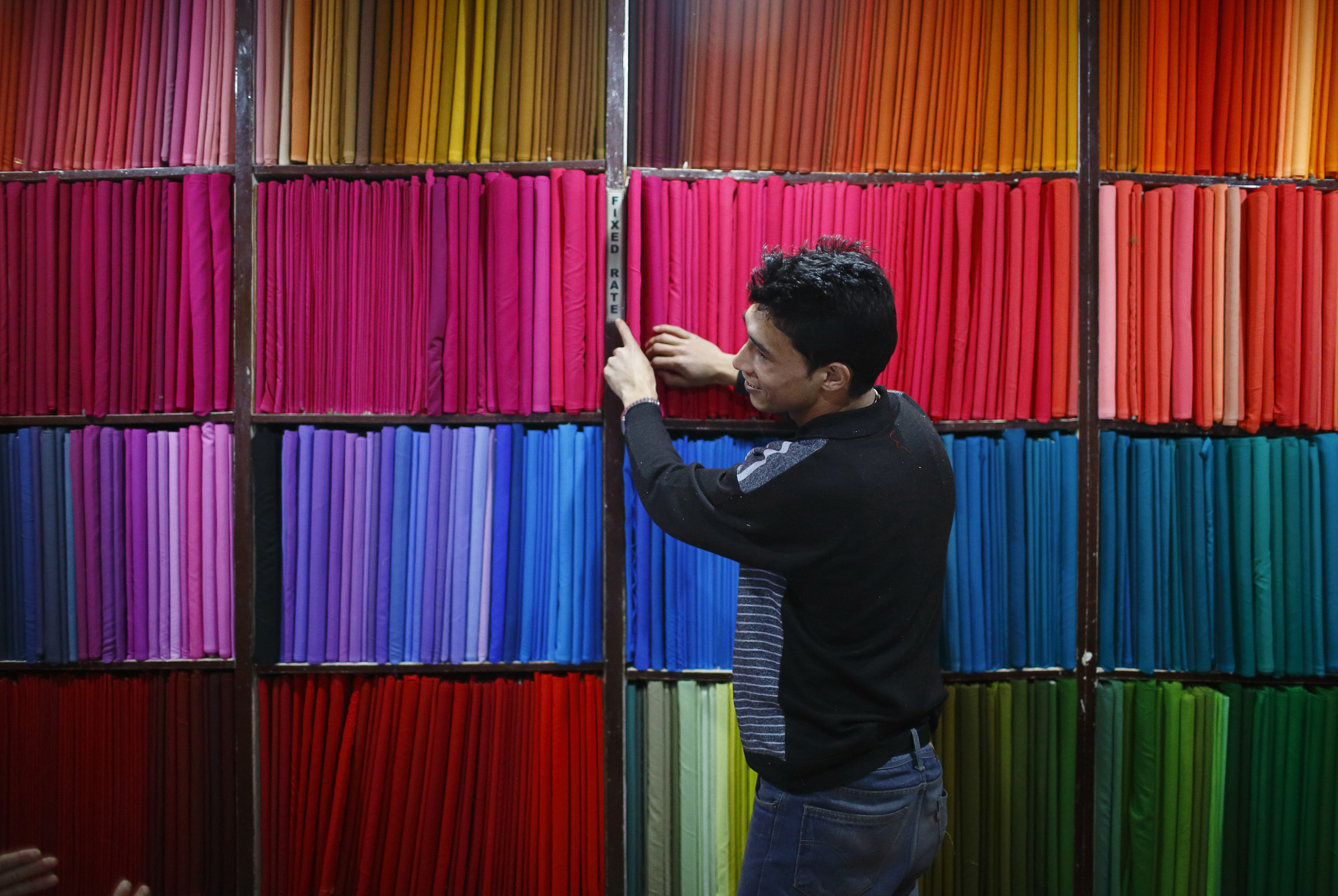 A salesman arranges cotton cloths kept for sale inside a shop in Kathmandu