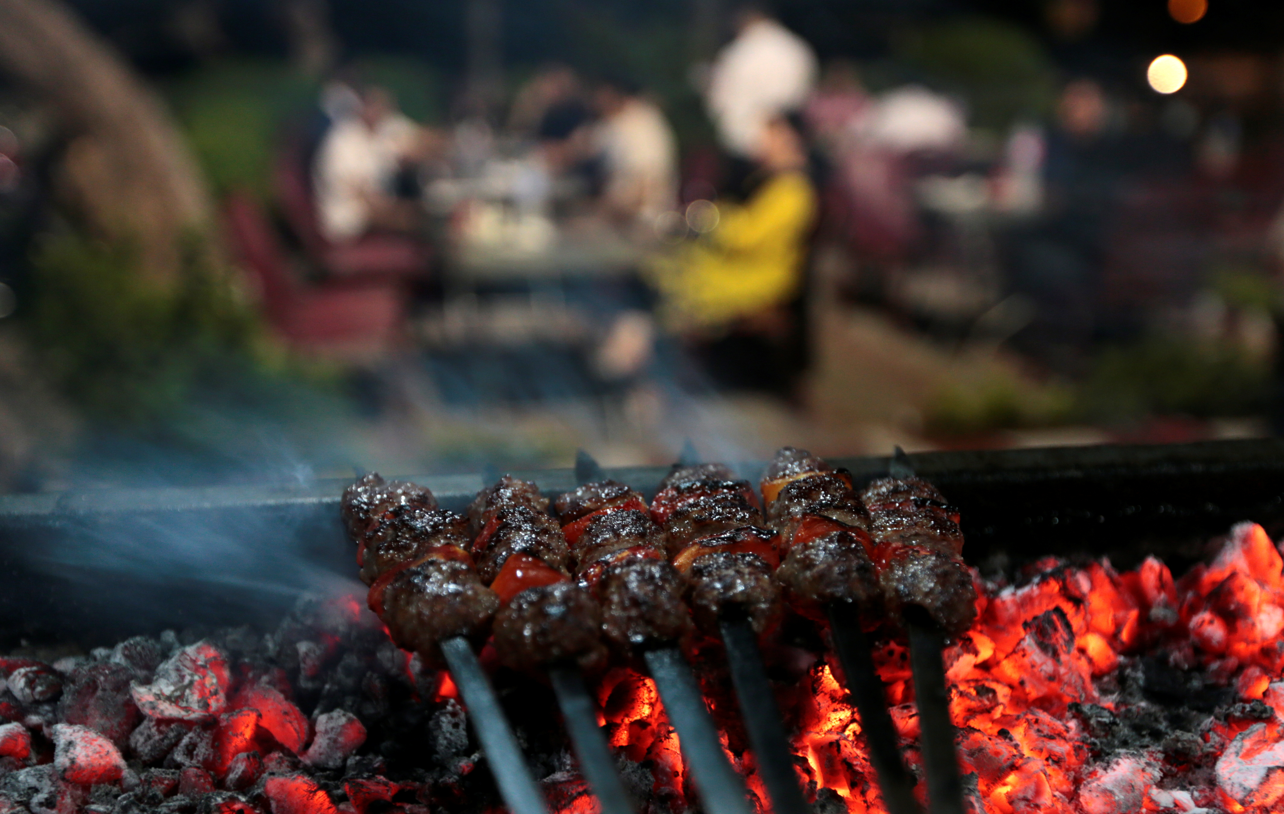 Minced meat kebab is seen being cooked on a barbecue as restaurant customers have dinner in Islamabad