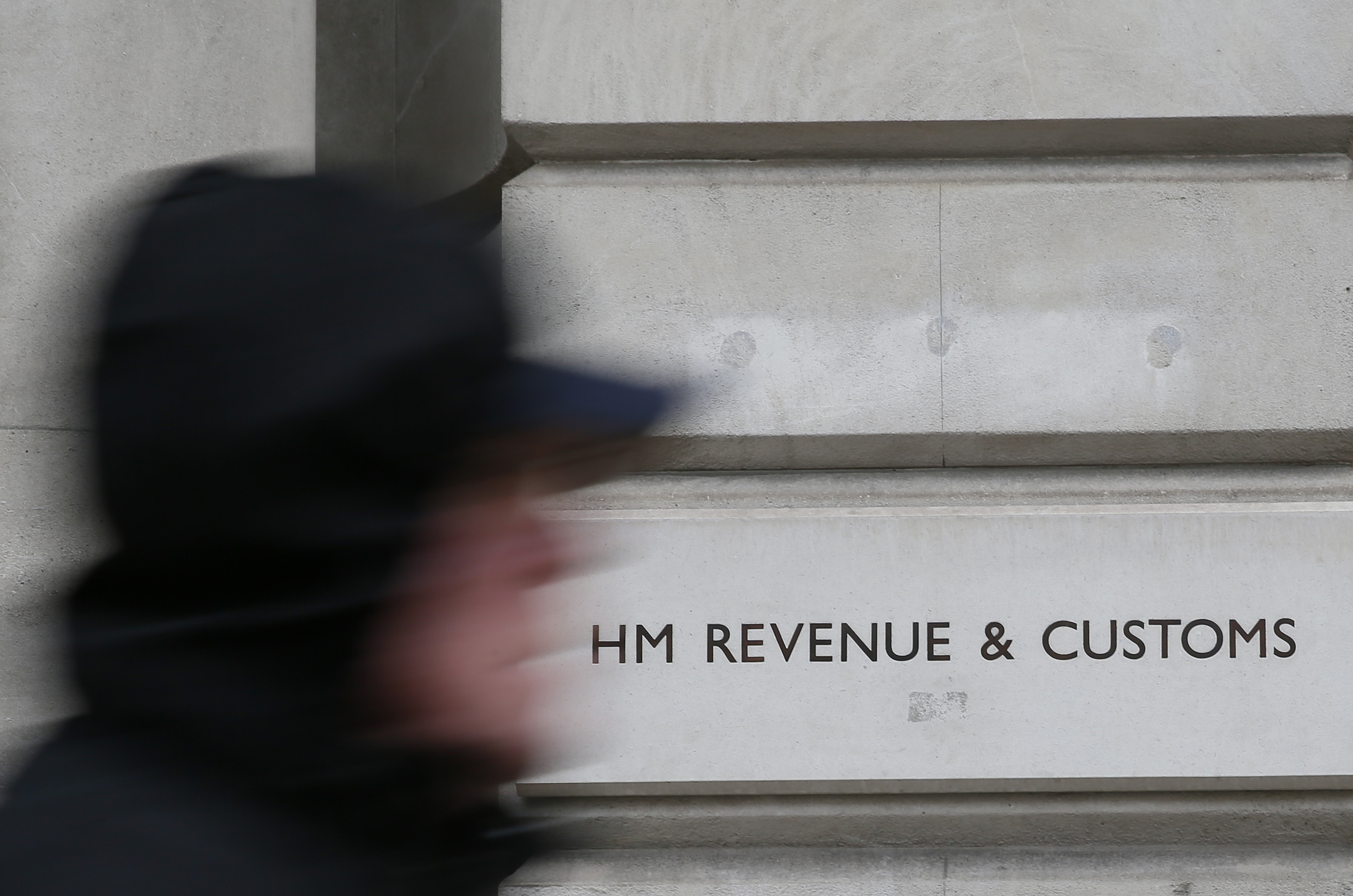 A pedestrian walks past the headquarters of Her Majesty's Revenue and Customs (HMRC) in central London