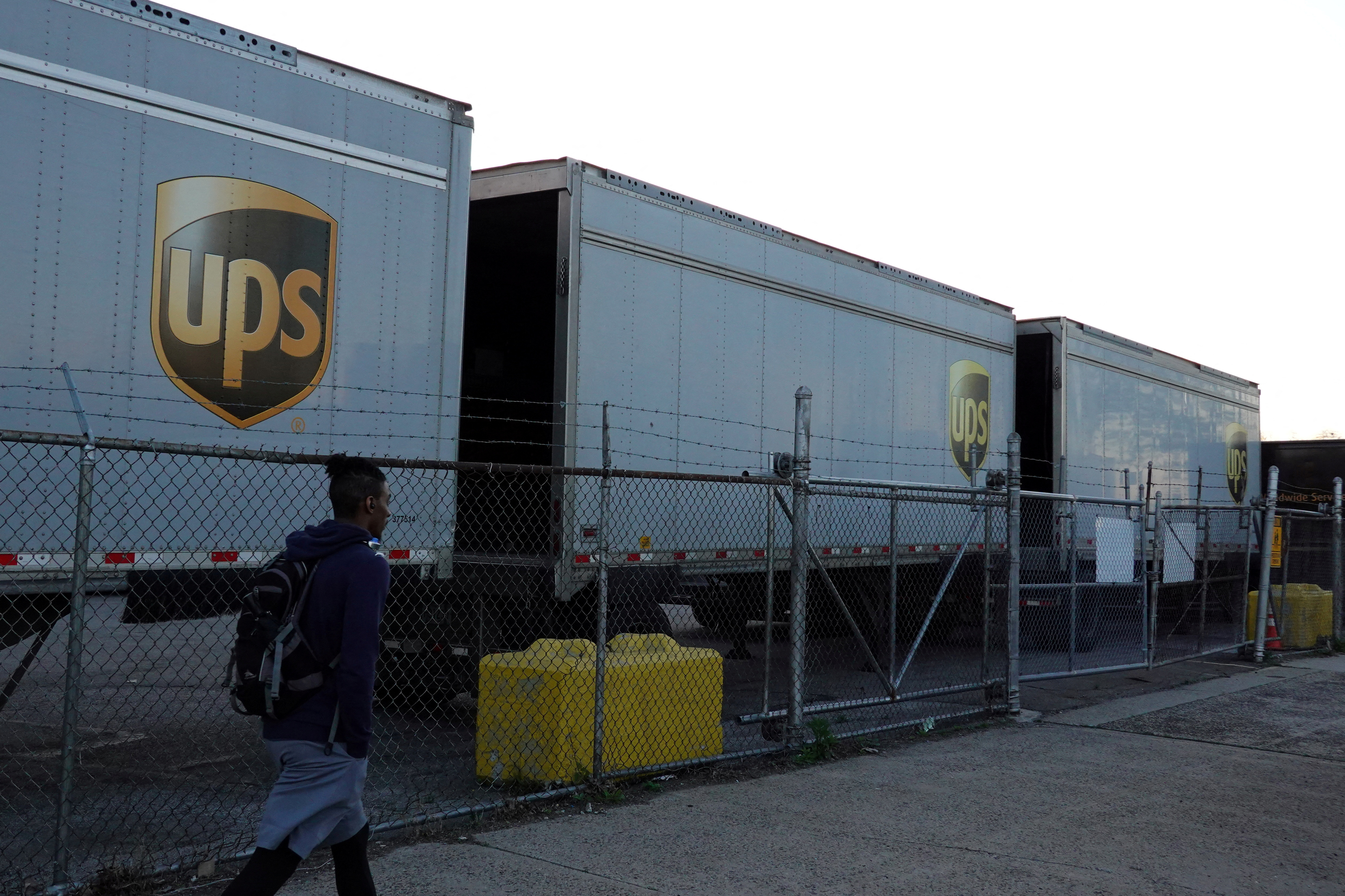 A person walks by United Parcel Service (UPS) trailers at a facility in Brooklyn, New York City