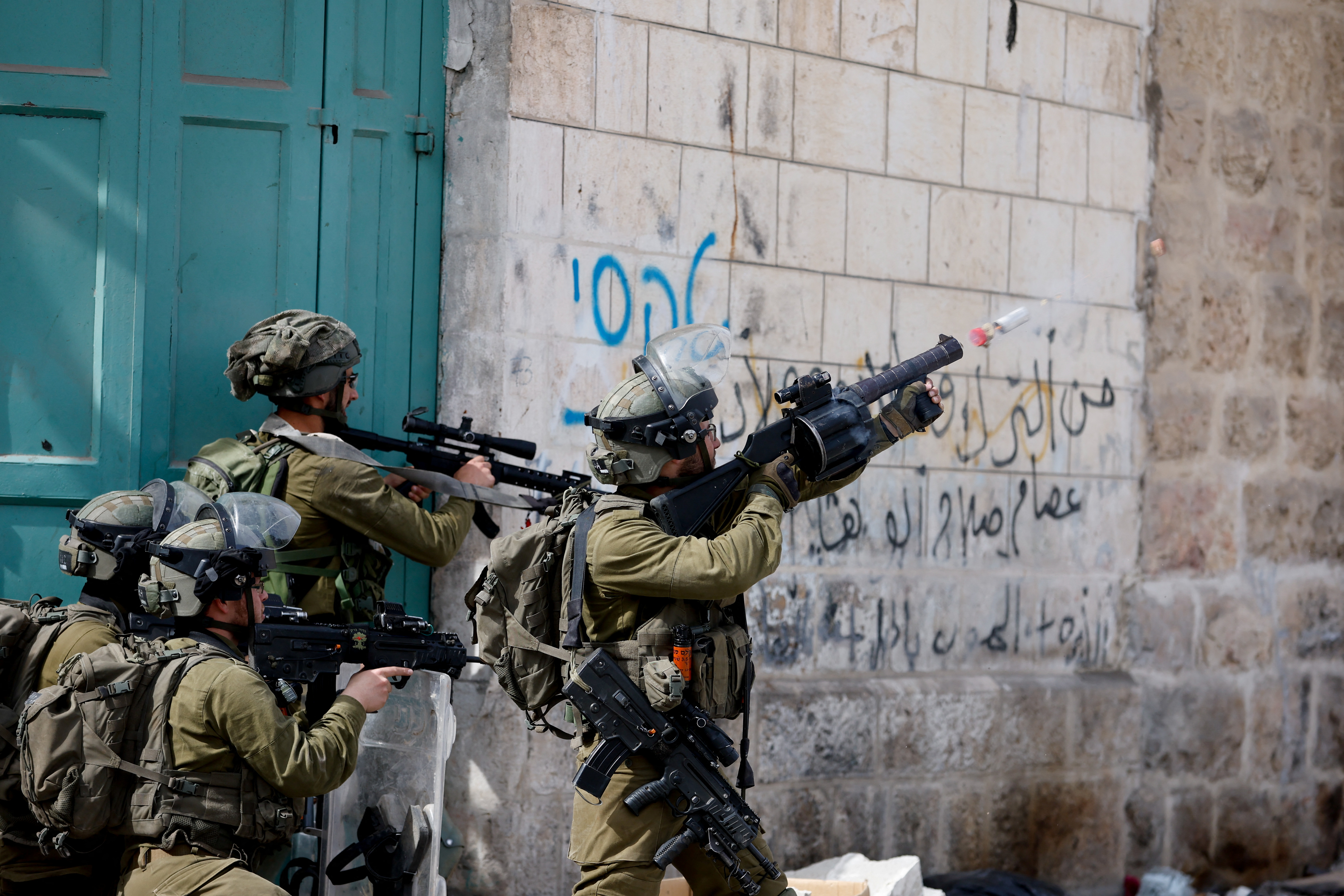 Israeli soldier uses a weapon amid clashes with Palestinian protesters, in Hebron