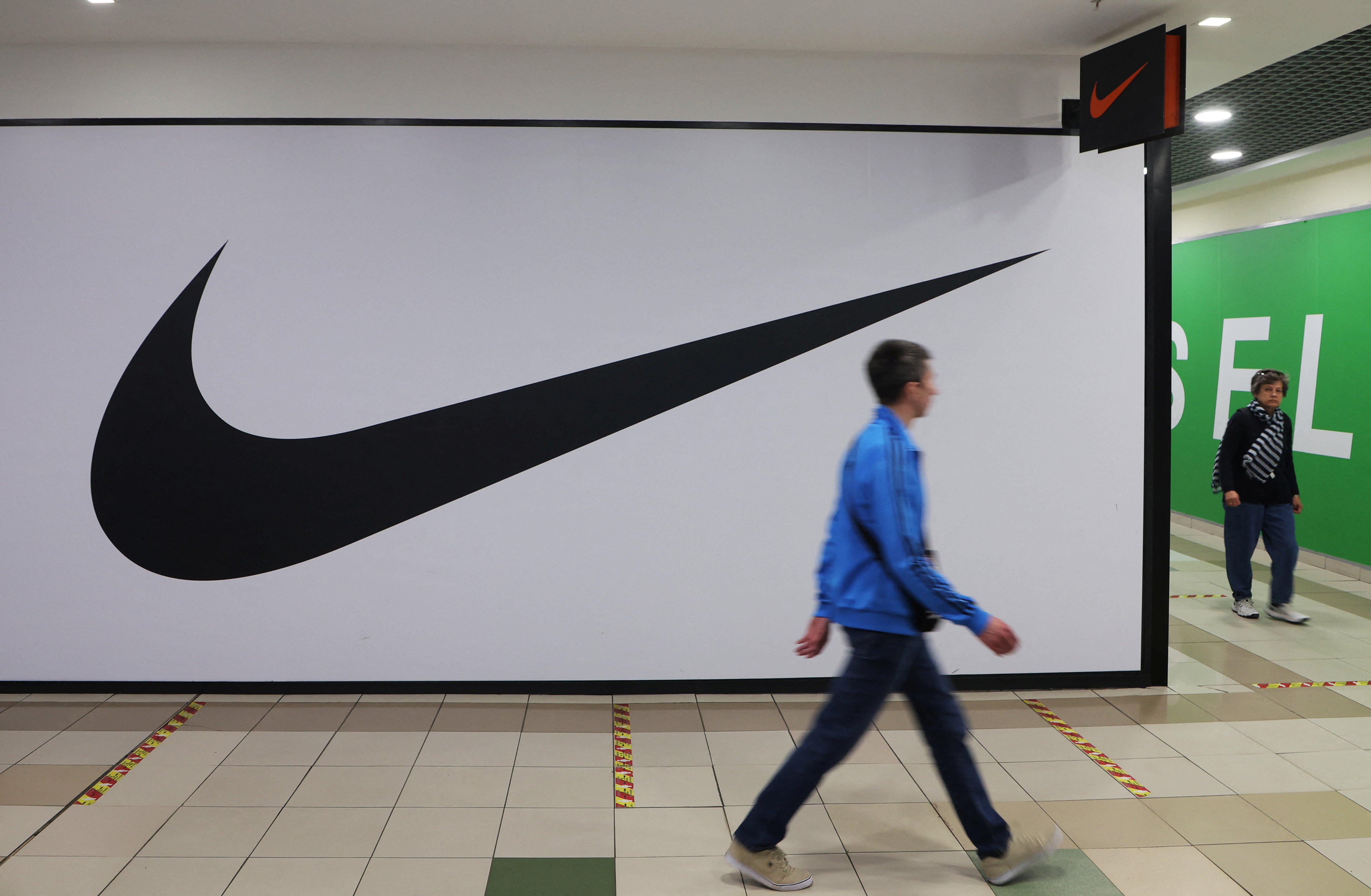 Mensen lopen langs een gesloten winkel van Nike in Sint-Petersburg