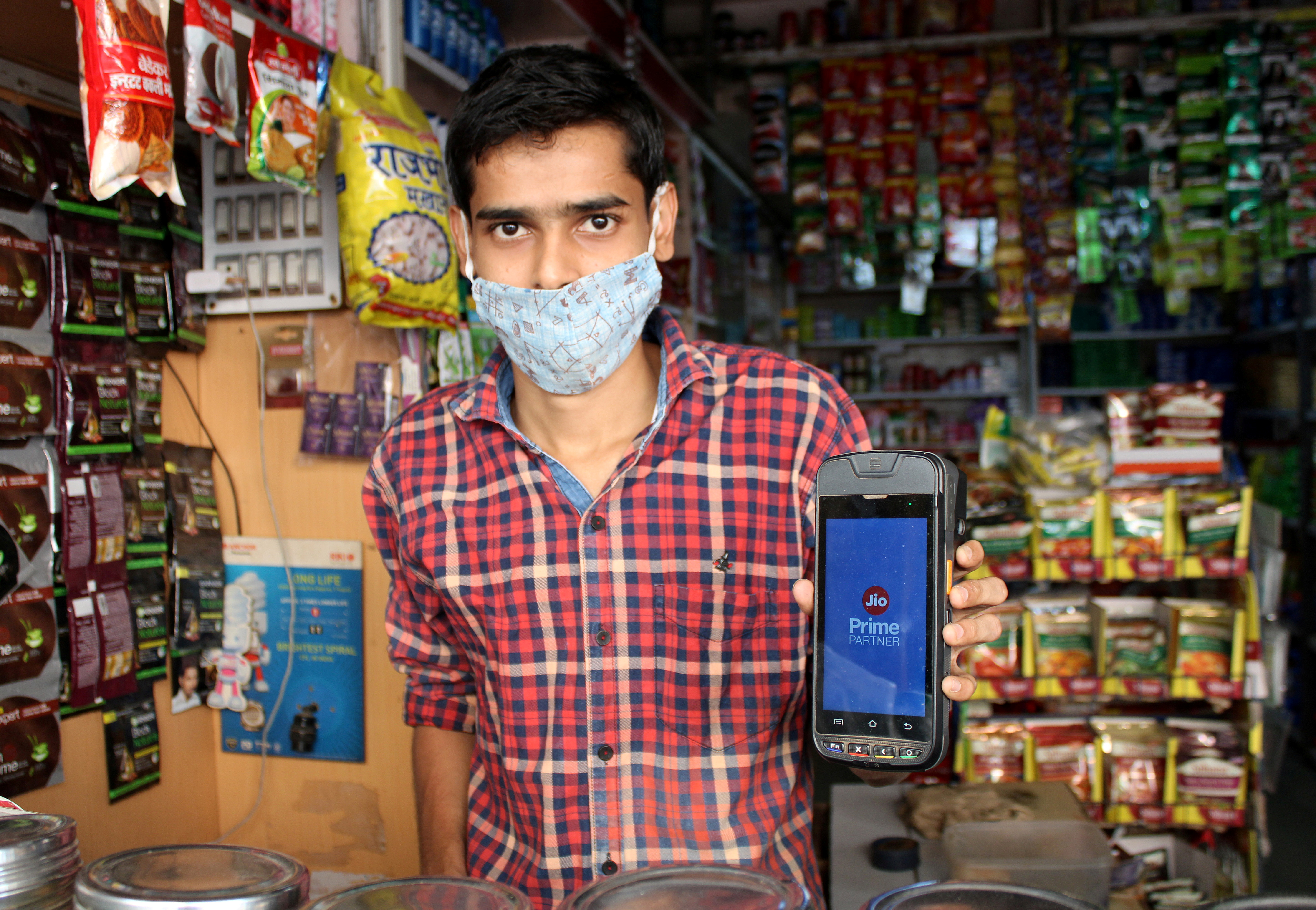 A shopkeeper selling consumer goods displays Reliance's JioMart point-of-sale machine that he uses to order supplies for his store in Sangli