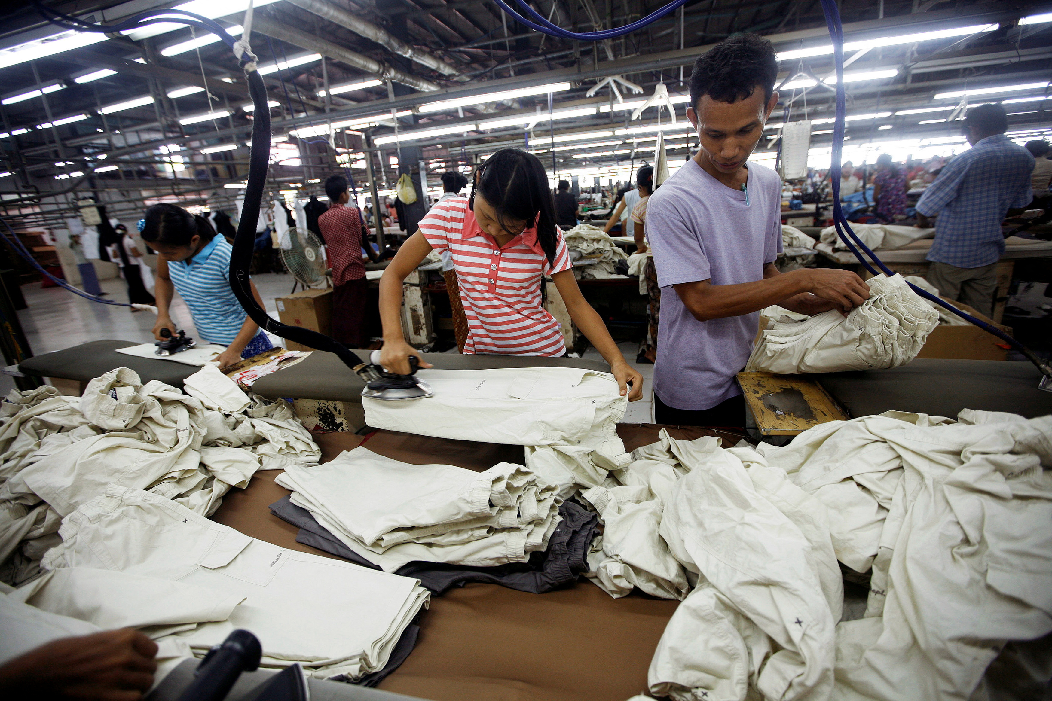 Workers iron and arrange clothing at a garment factory in Yangon
