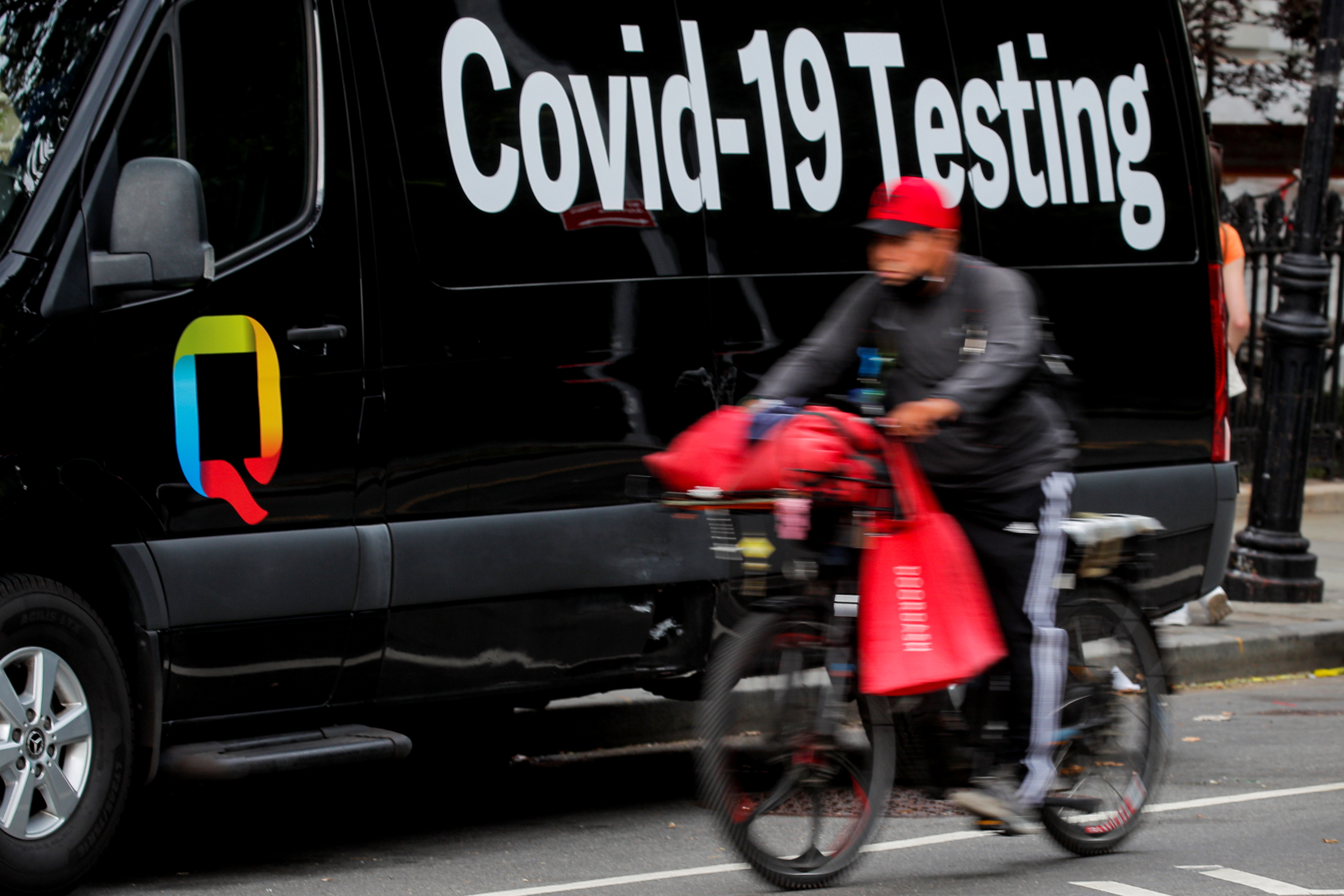A food delivery person passes by a COVID-19 mobile testing van in New York
