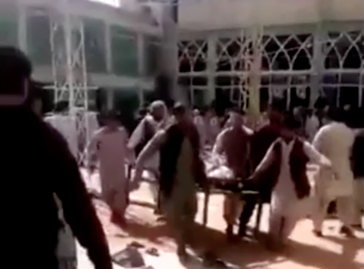 Des personnes transportent une victime après une grande explosion dans une mosquée chiite de Kandahar, en Afghanistan, le 15 octobre 2021. via REUTERS TV