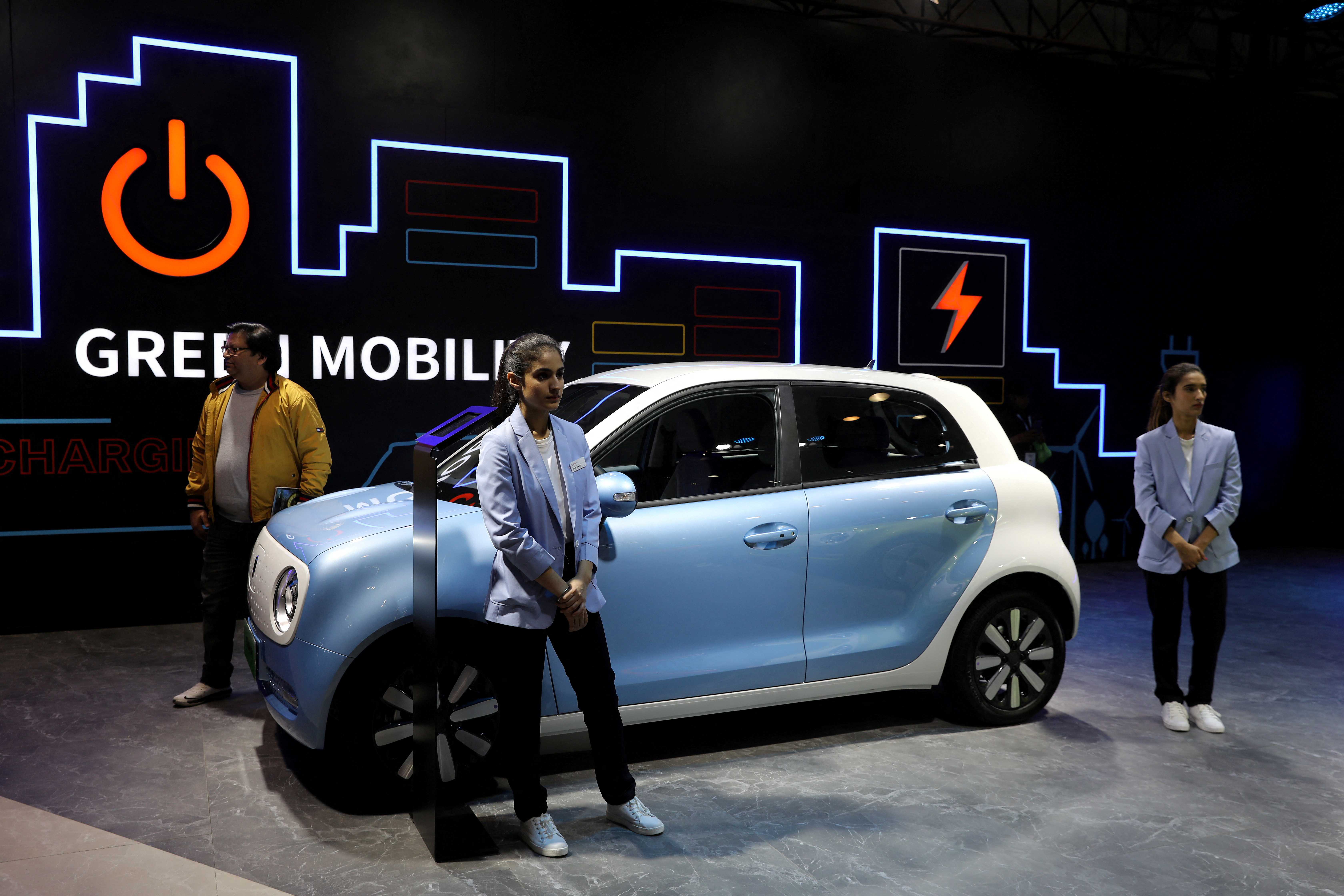 Models pose next to Great Wall Motors (GWM) GWM R1 electric car at its pavilion at the India Auto Expo 2020 in Greater Noida