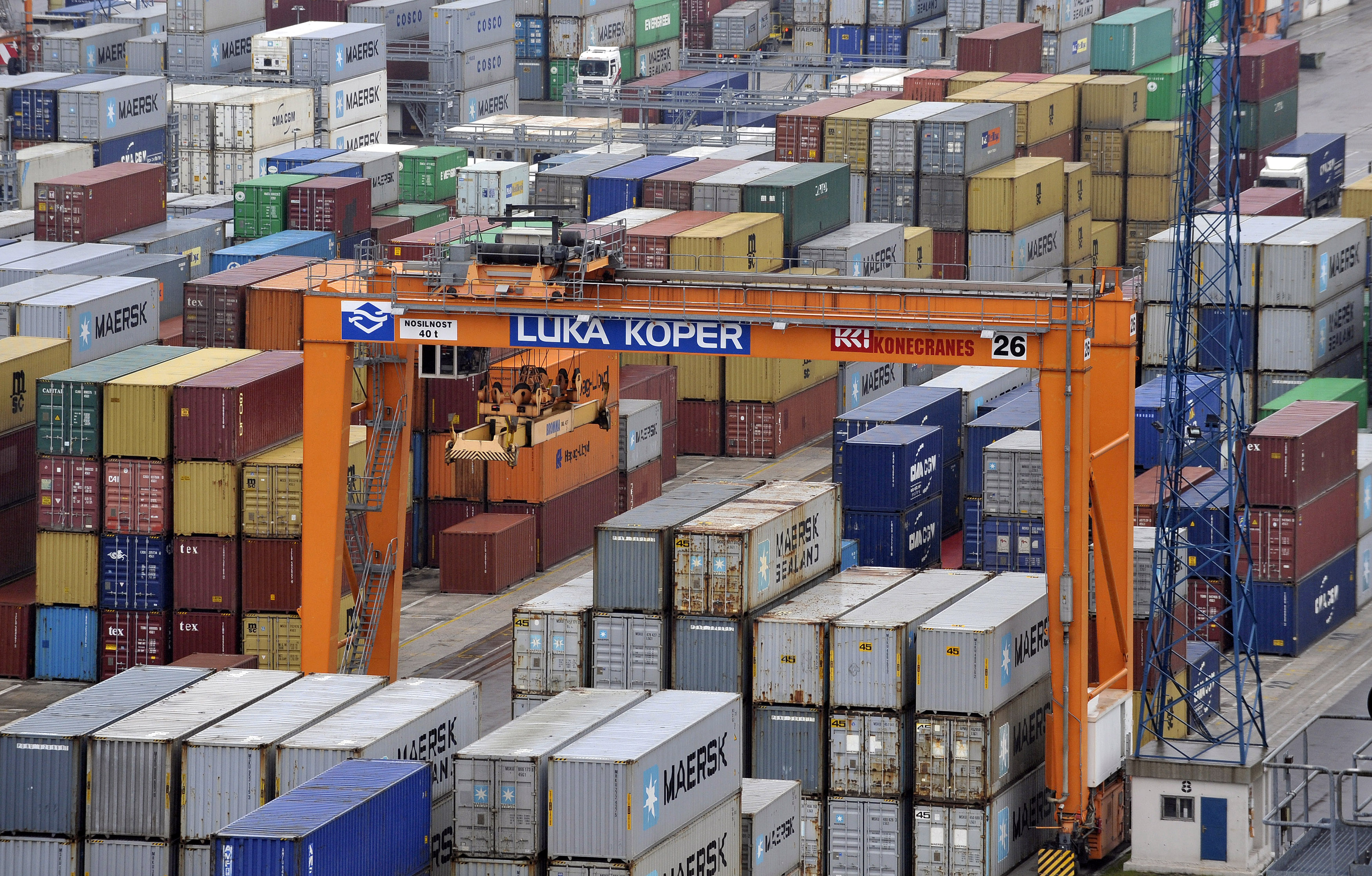 A crane is pictured next to lined up containers at the Port of Koper
