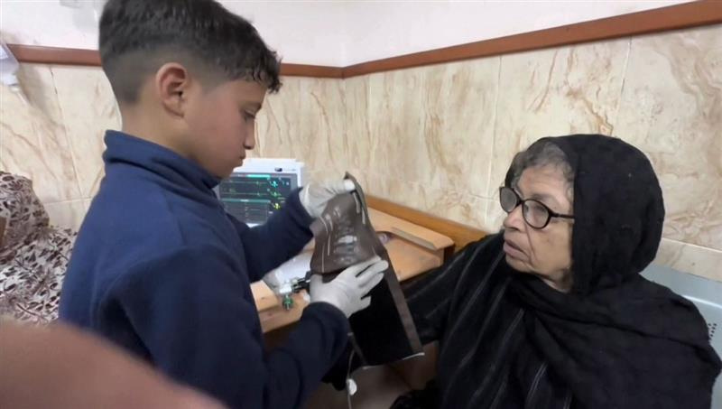 Zakaria Sarsak, 12, helps a patient with a blood pressure test at the Al-Aqsa Hospital in Gaza in this undated frame grab taken from video. REUTERS