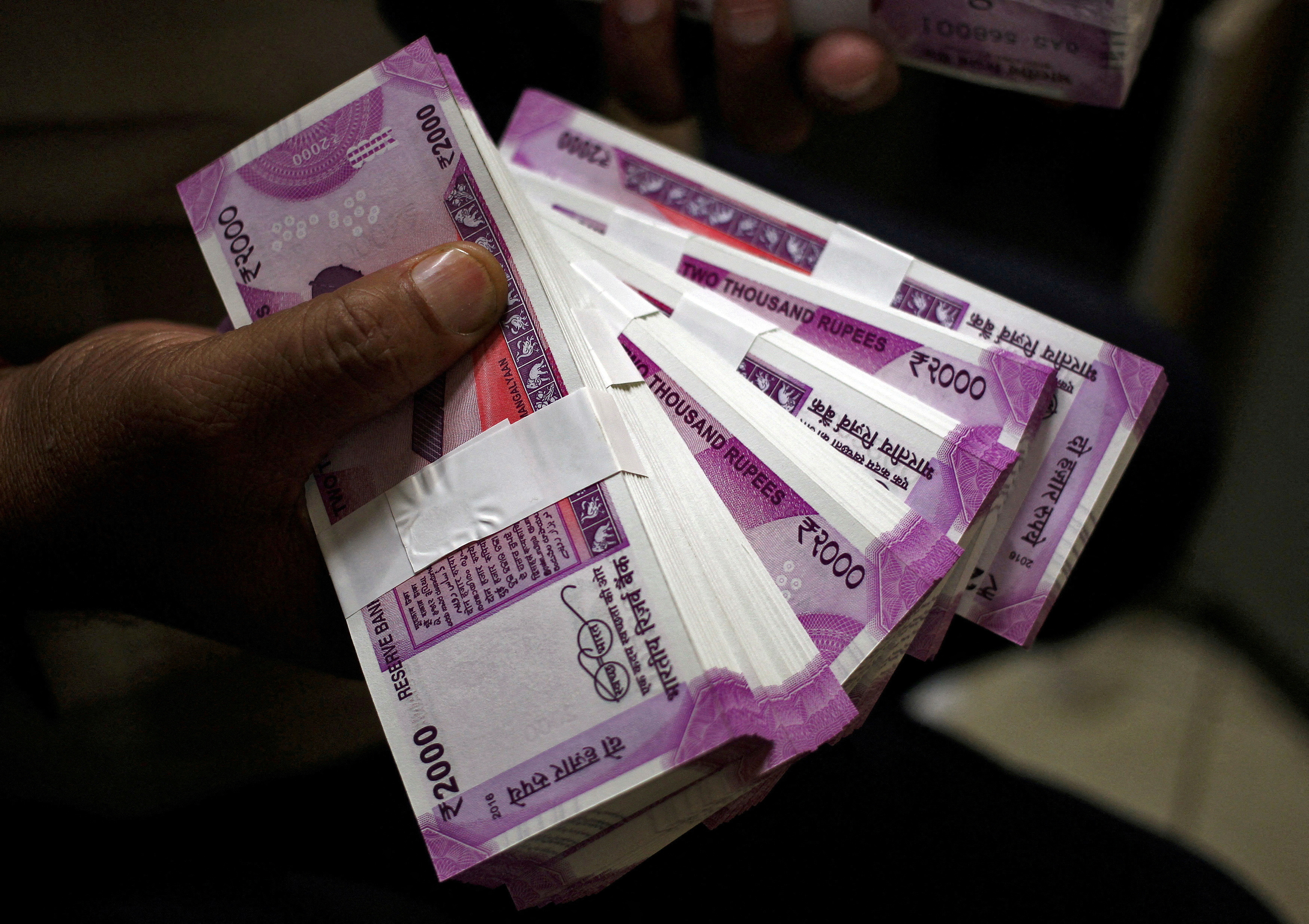 FILE PHOTO: A cashier displays 2000 Indian rupee banknotes inside a bank in Jammu
