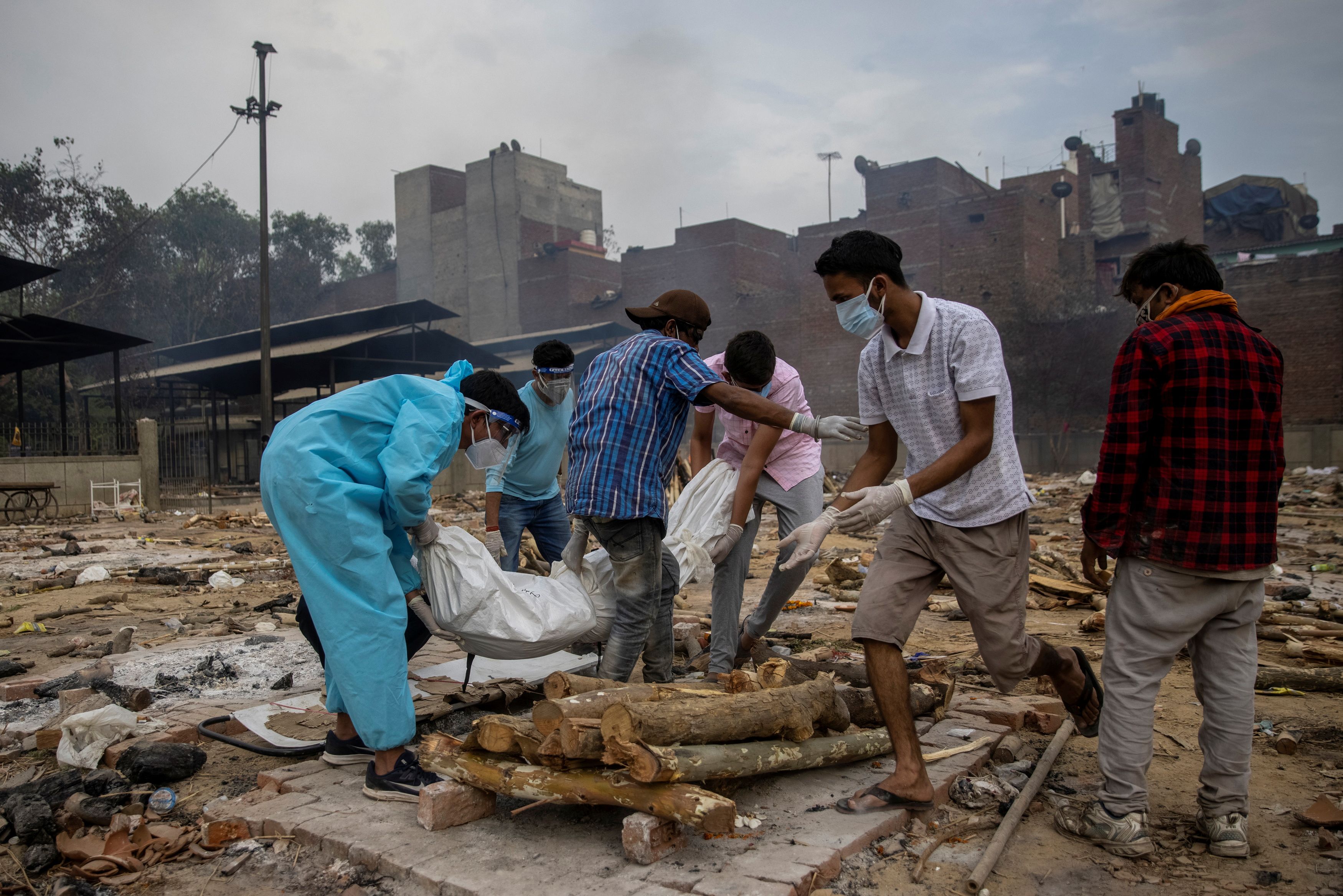 Pranav Mishra is helped by his relatives to place the body of his mother Mamta Mishra, who died from the coronavirus disease (COVID-19), on a pyre for her cremation at a crematorium ground in New Delhi