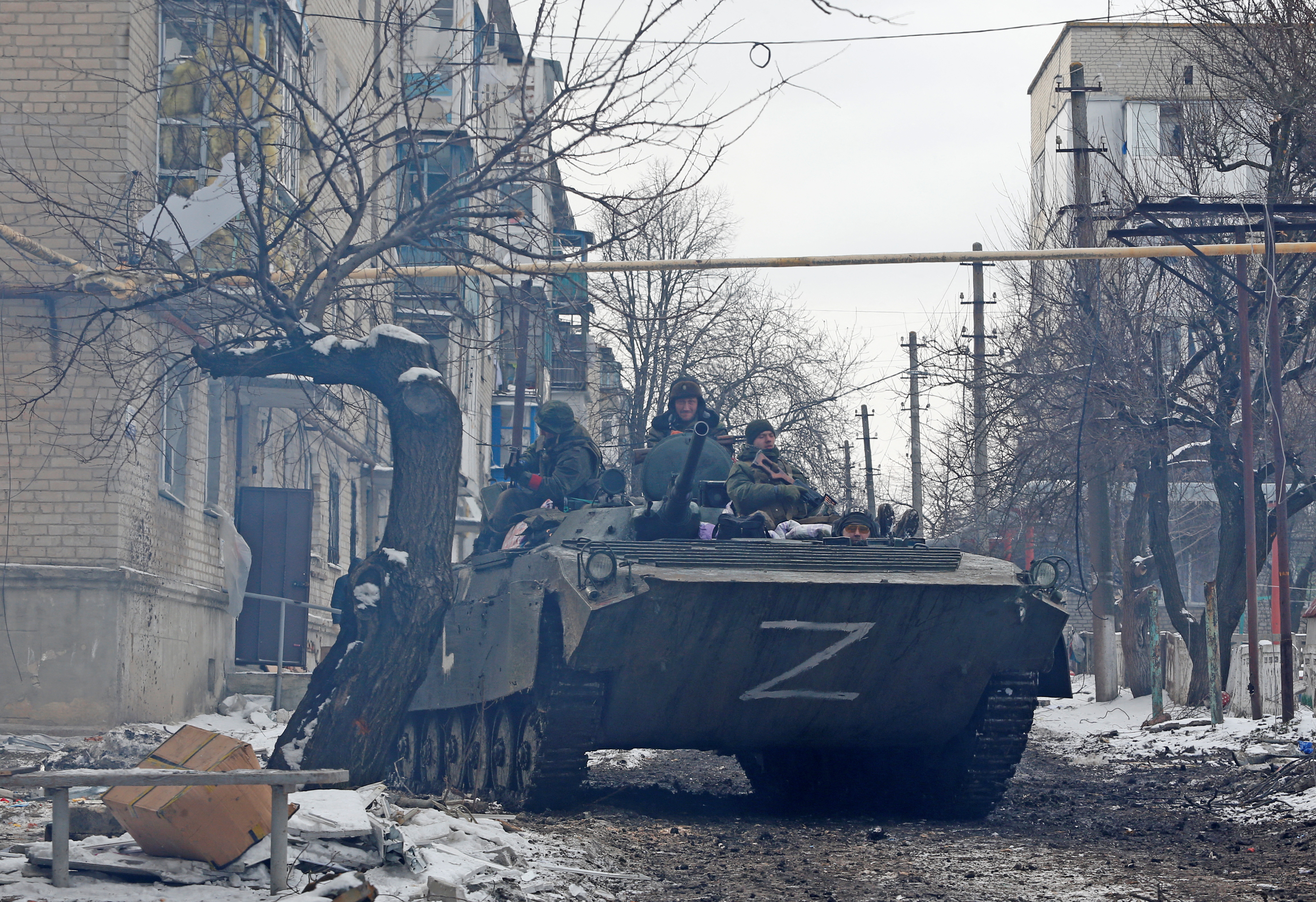 Service members of pro-Russian troops drive an armoured vehicle in a residential area in Volnovakha