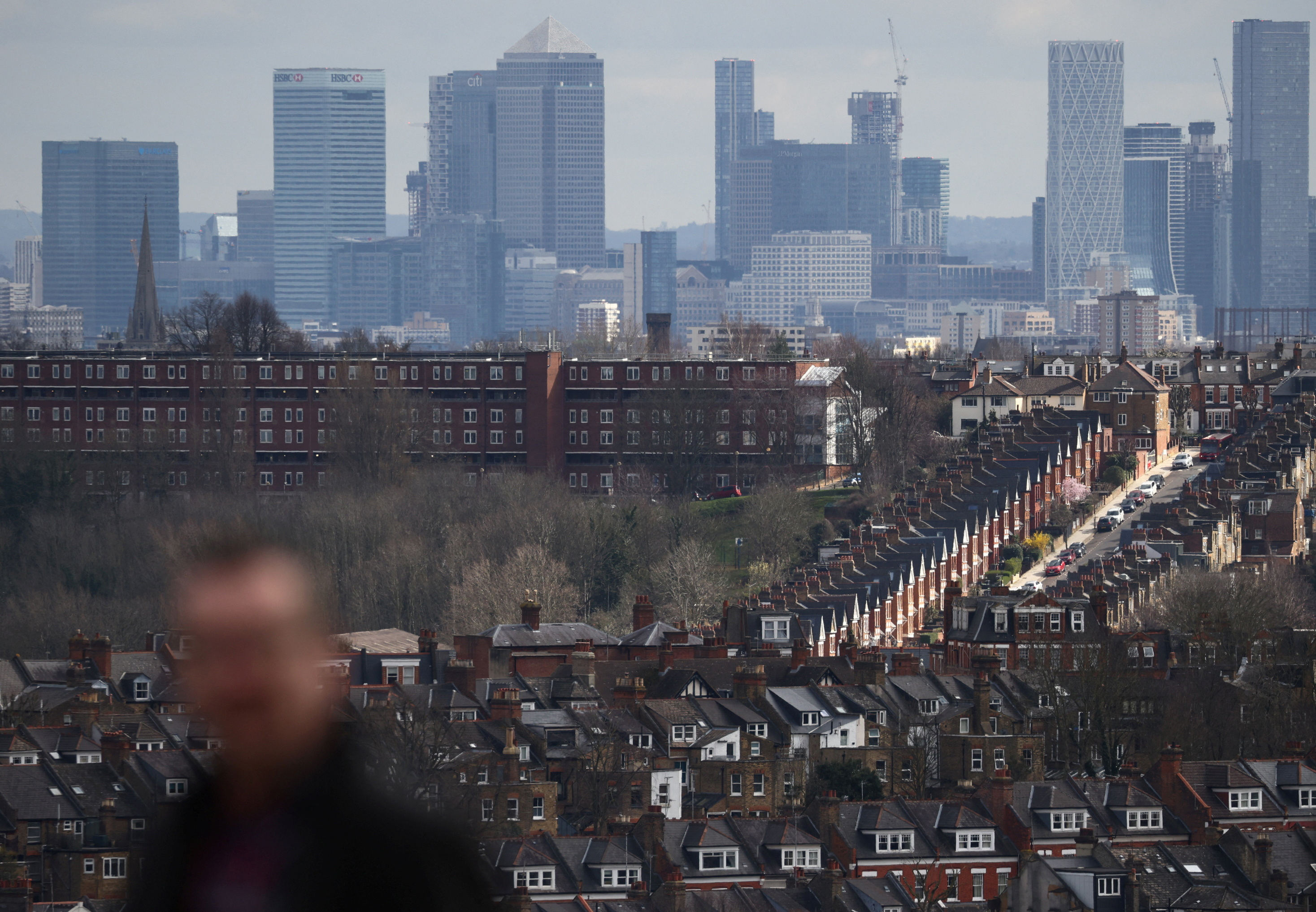 Rows of houses lie in front of the Canary Wharf skyline in London