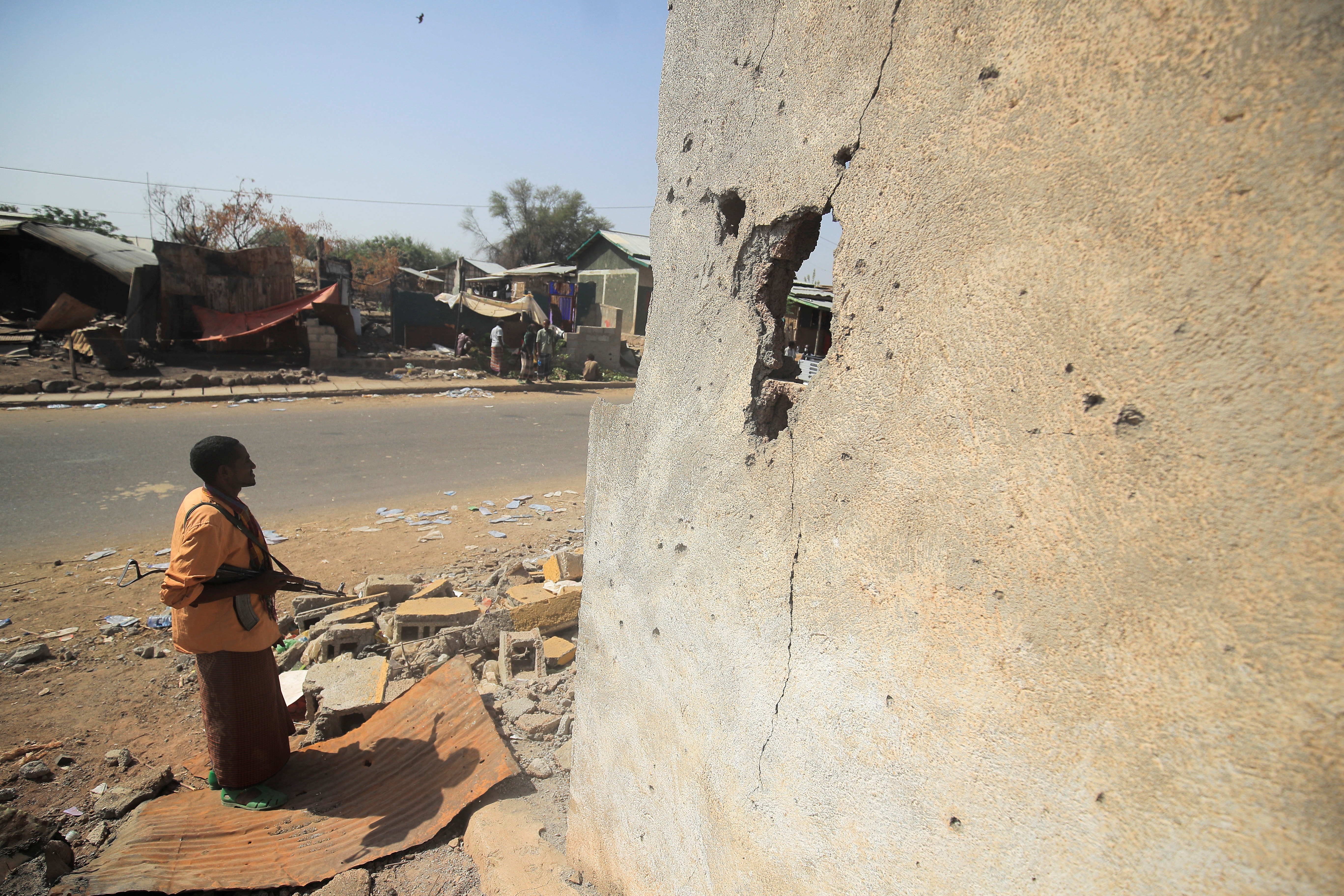 An armed militia stands next to a house damaged during the fight between the Ethiopian National Defence Forces (ENDF) and the Tigray People's Liberation Front (TPLF) forces, in Kasagita town