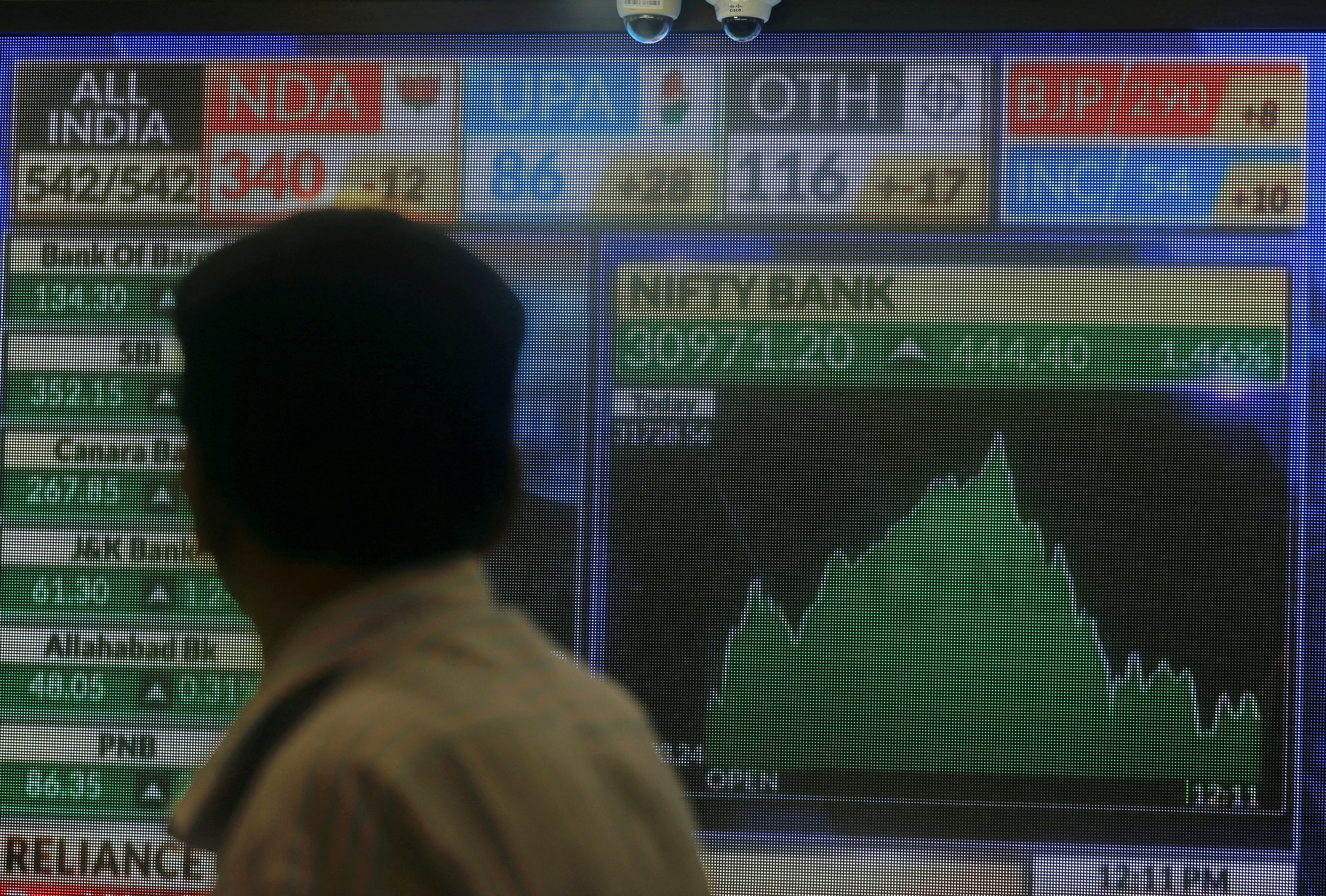 A man looks at a screen displaying news of markets update inside the Bombay Stock Exchange (BSE) building in Mumbai