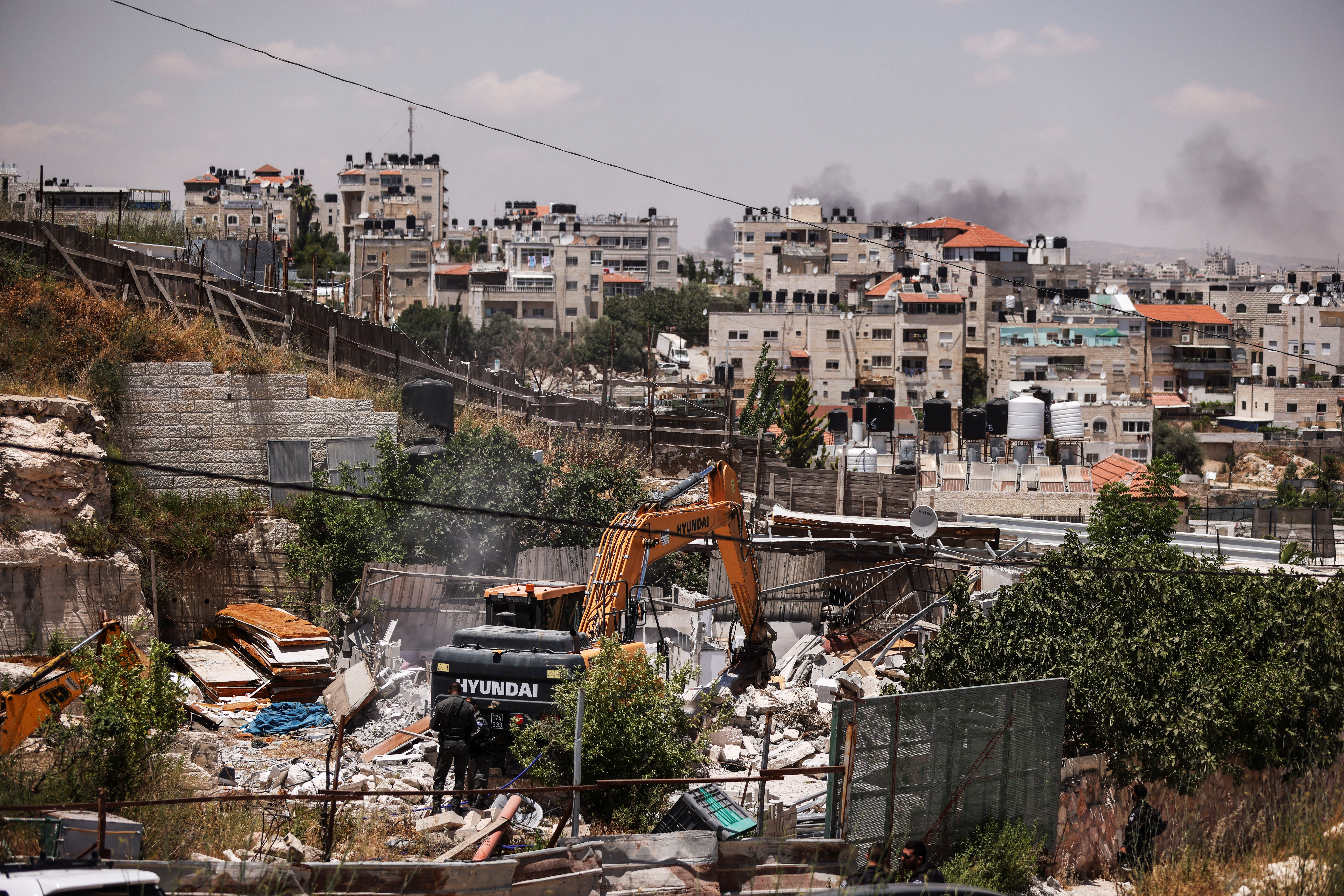 Israeli border policemen stand by a bulldozer as it demolishes a house in East Jerusalem