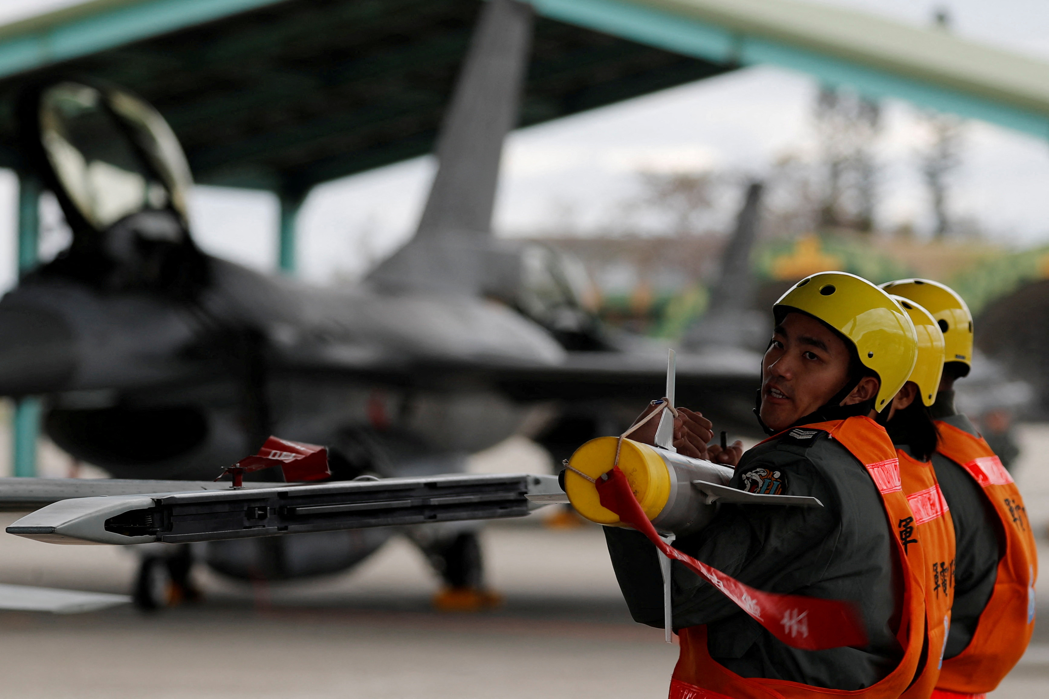 Air force crews lift an AIM-9 Sidewinder air-to-air missiles to be loaded onto Northrop F-5 fighter during a military drill at Zhi-Hang Air Base in Taitung