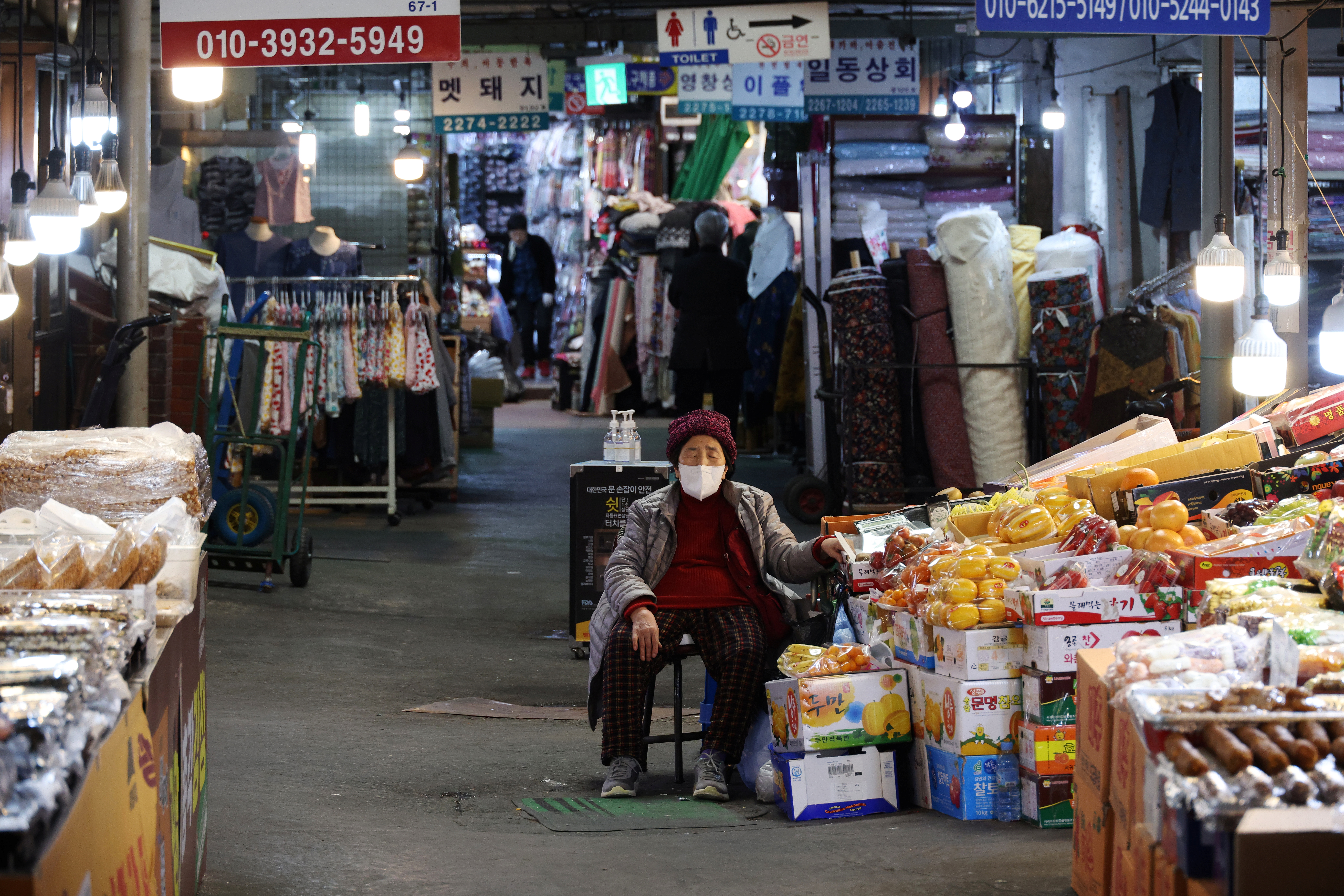 A shopkeeper naps as she waits for customers at a traditional market in Seoul