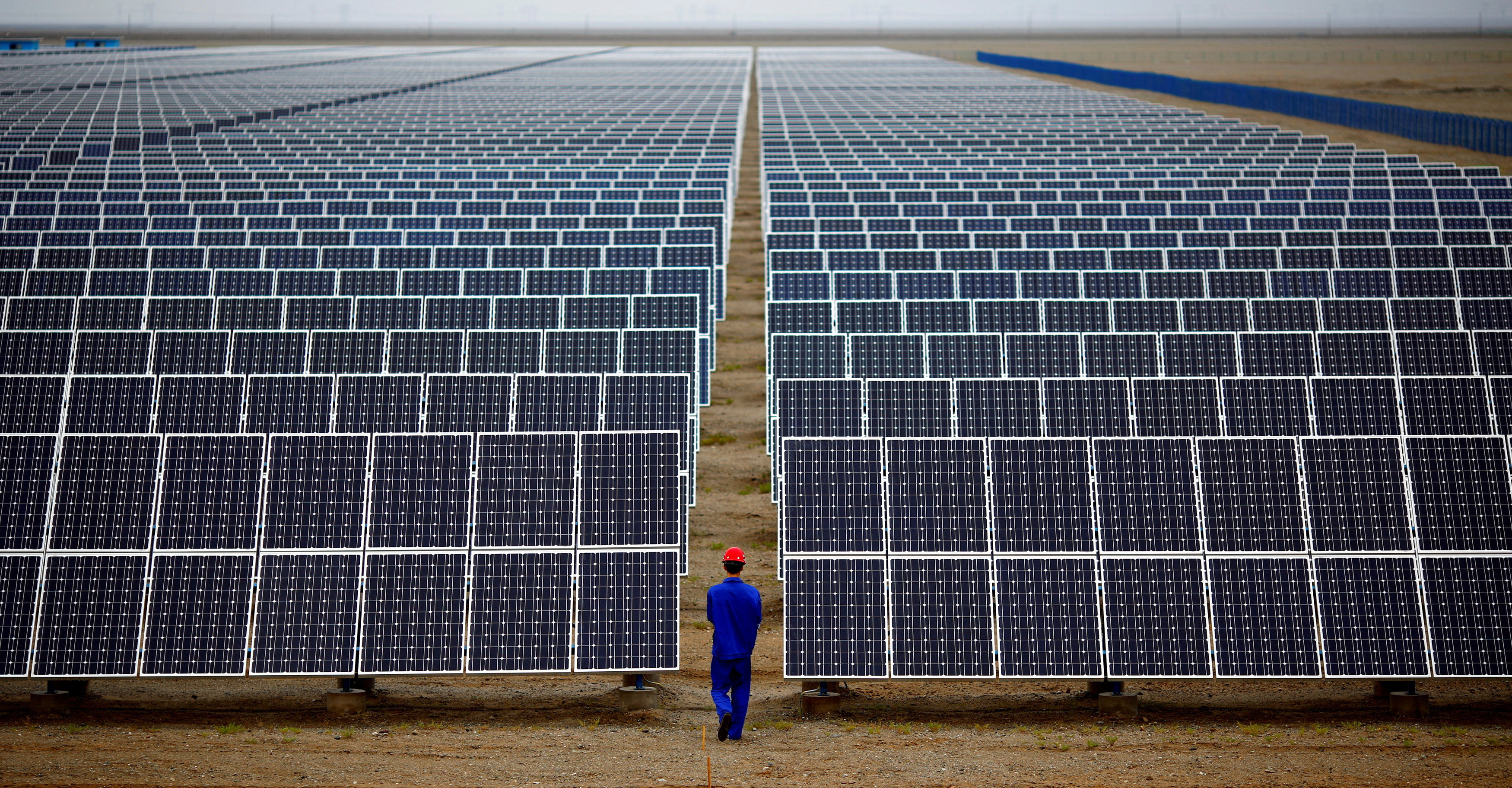 Một công nhân kiểm tra các tấm pin mặt trời tại trang trại năng lượng mặt trời ở Đôn Hoàng, cách Lan Châu, tỉnh Cam Túc 950km về phía tây bắc