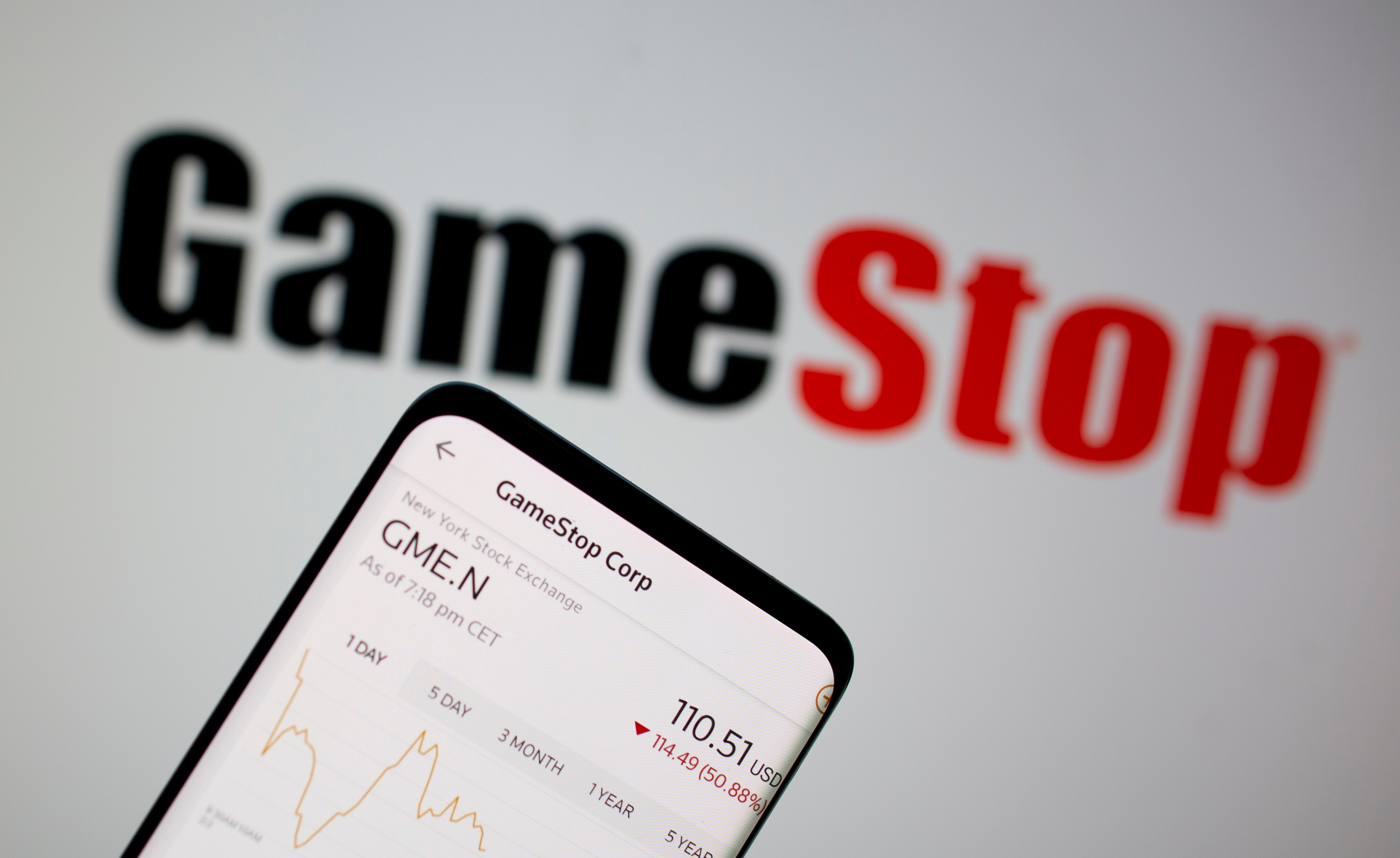 GameStop stock graph is seen in front of the company's logo