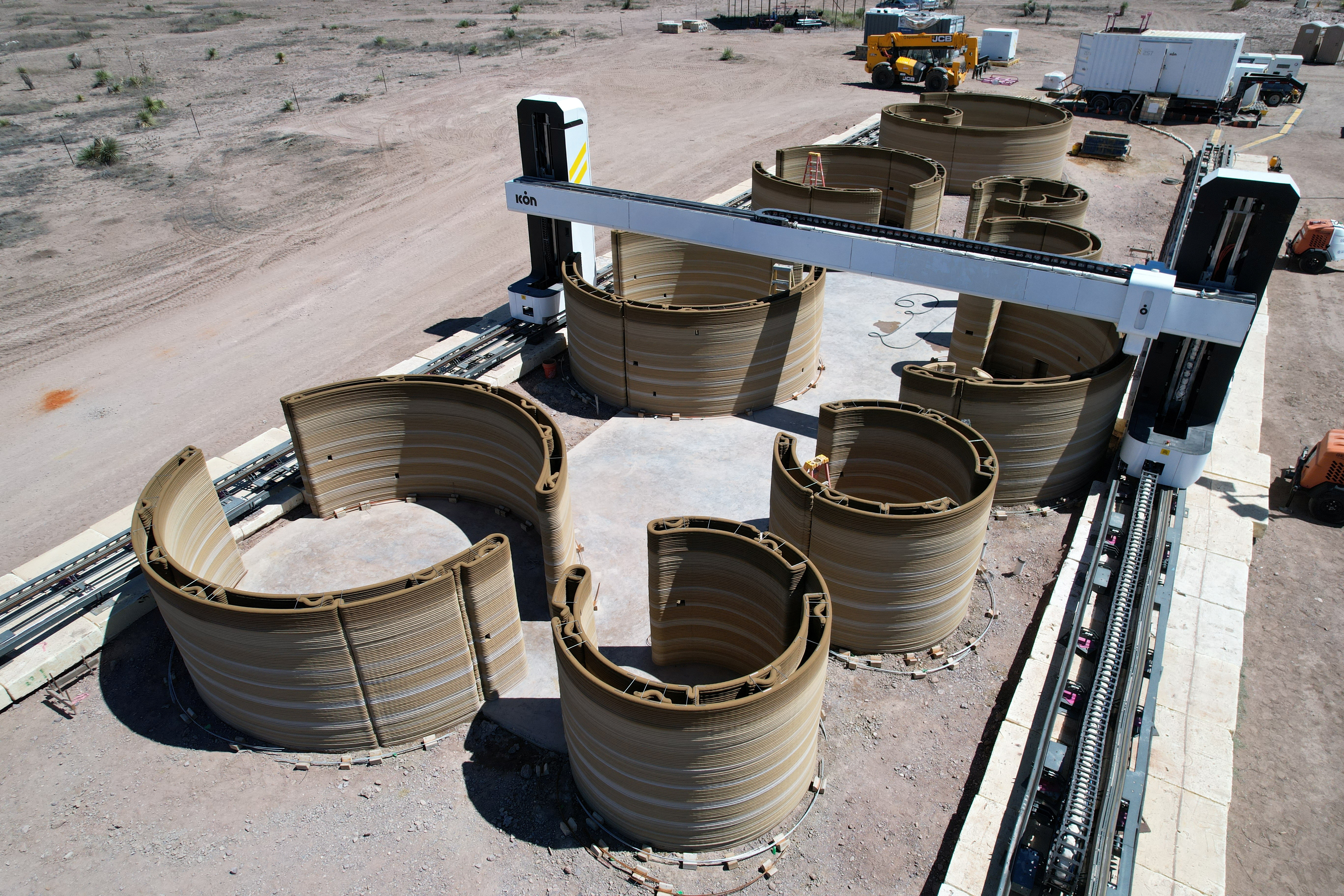 An aerial view of the first 3D-printed residential unit in foreground and first 3D-printed hotel unit in background of El Cosmico campground and hotel in Marfa