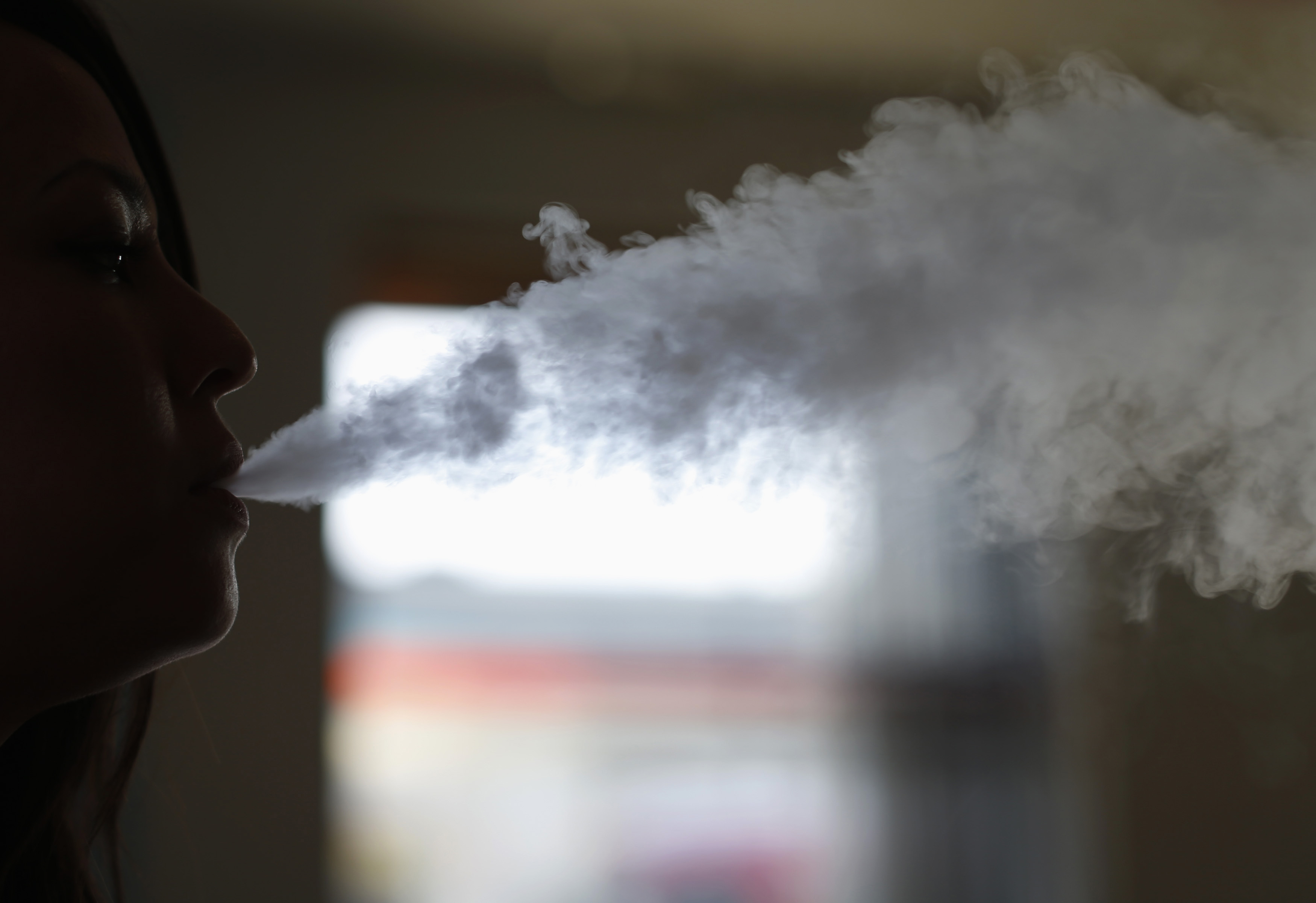 A woman exhales vapor from an electronic cigarette at a vapor bar in Los Angeles, California